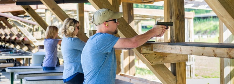 A man and two women shooting handguns at shooting range