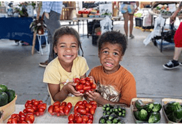 Kids standing by fresh fruits and vegetables