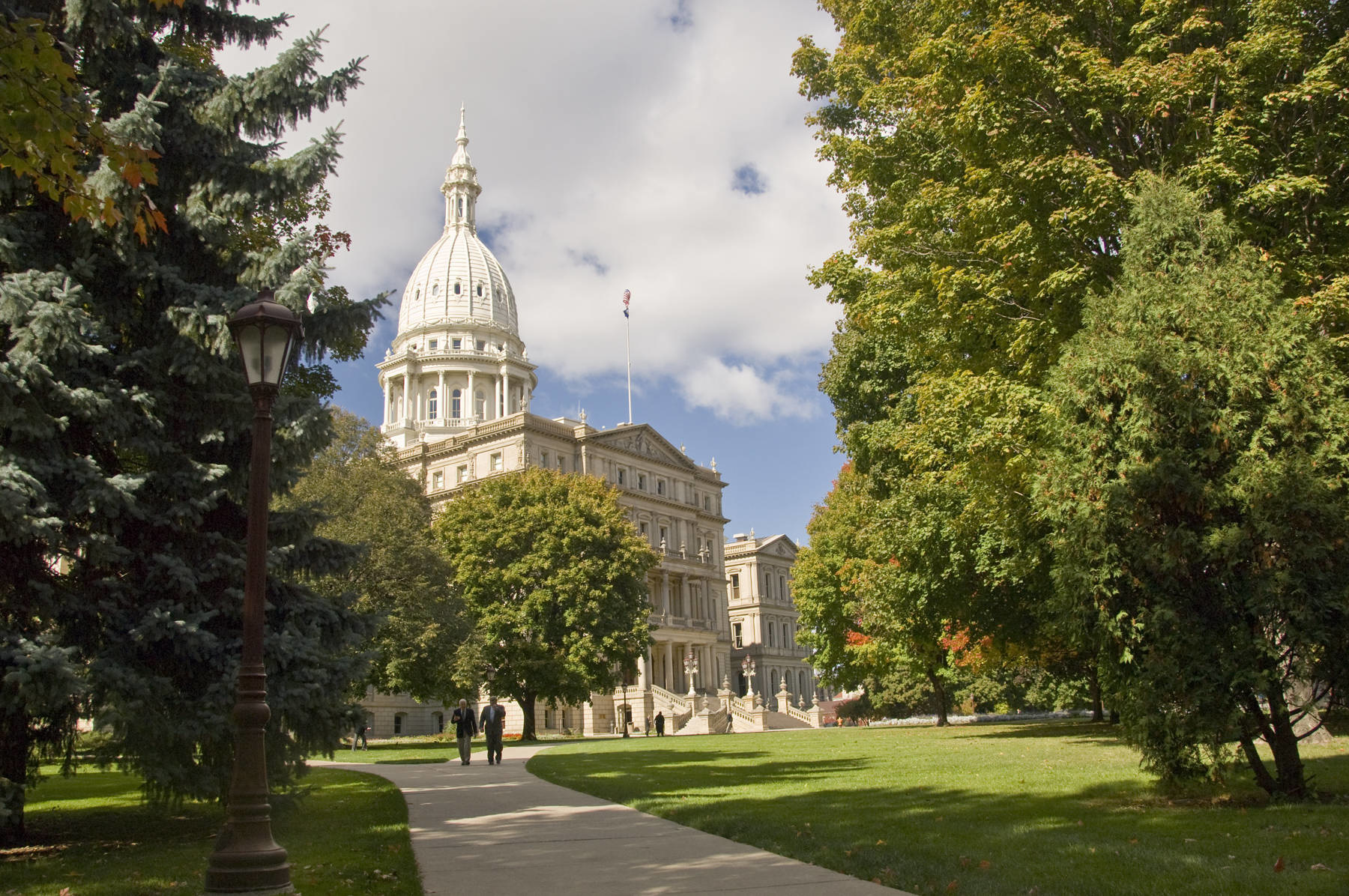 Photo of the Capitol and two people walking on the sidewalk.