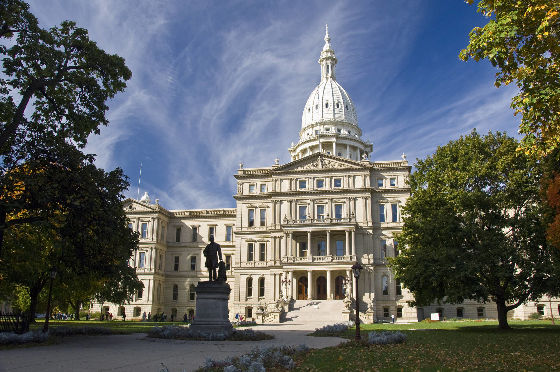 Photo of the Michigan State Capitol with statue in foreground.