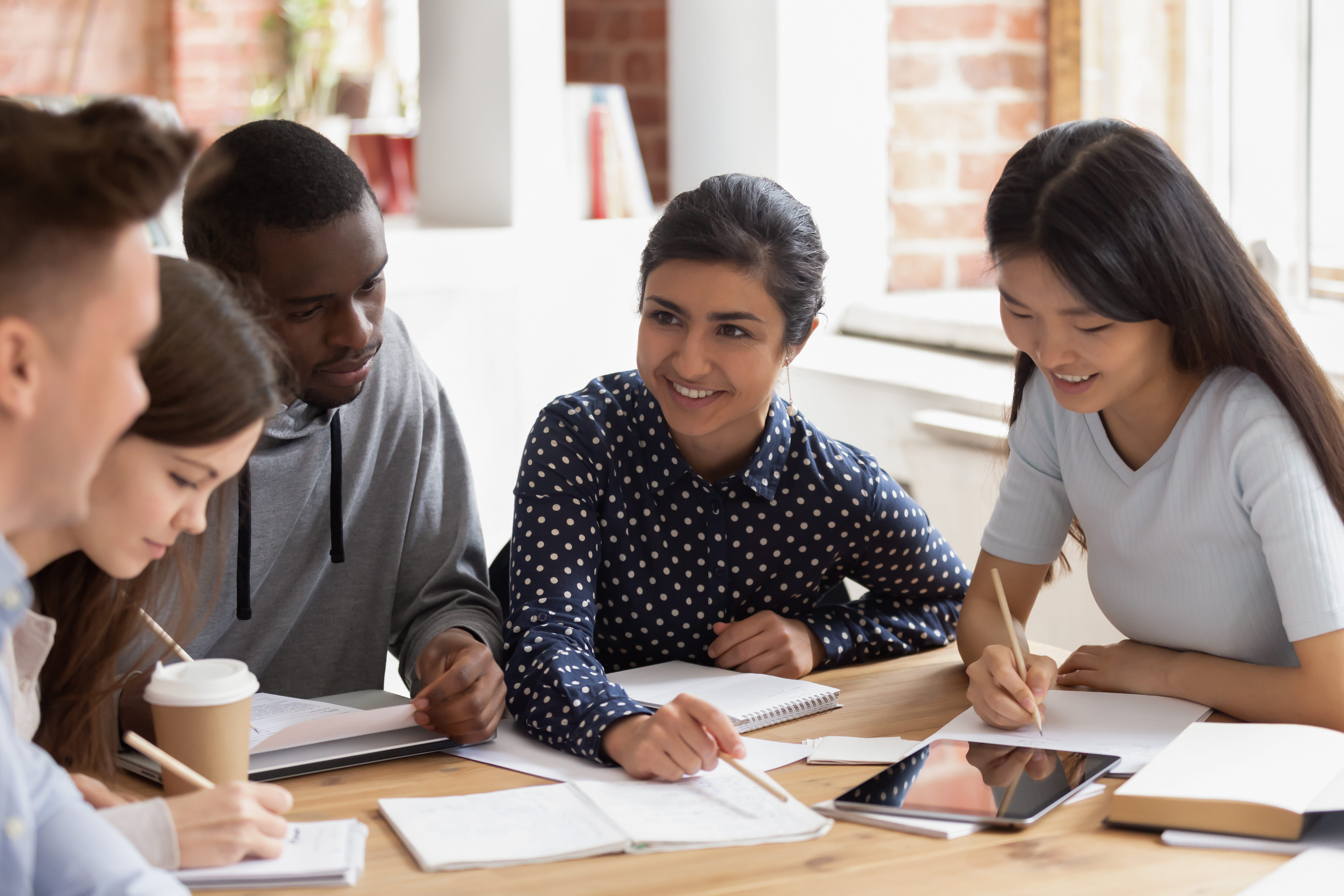 multinational students sitting at desk studying together