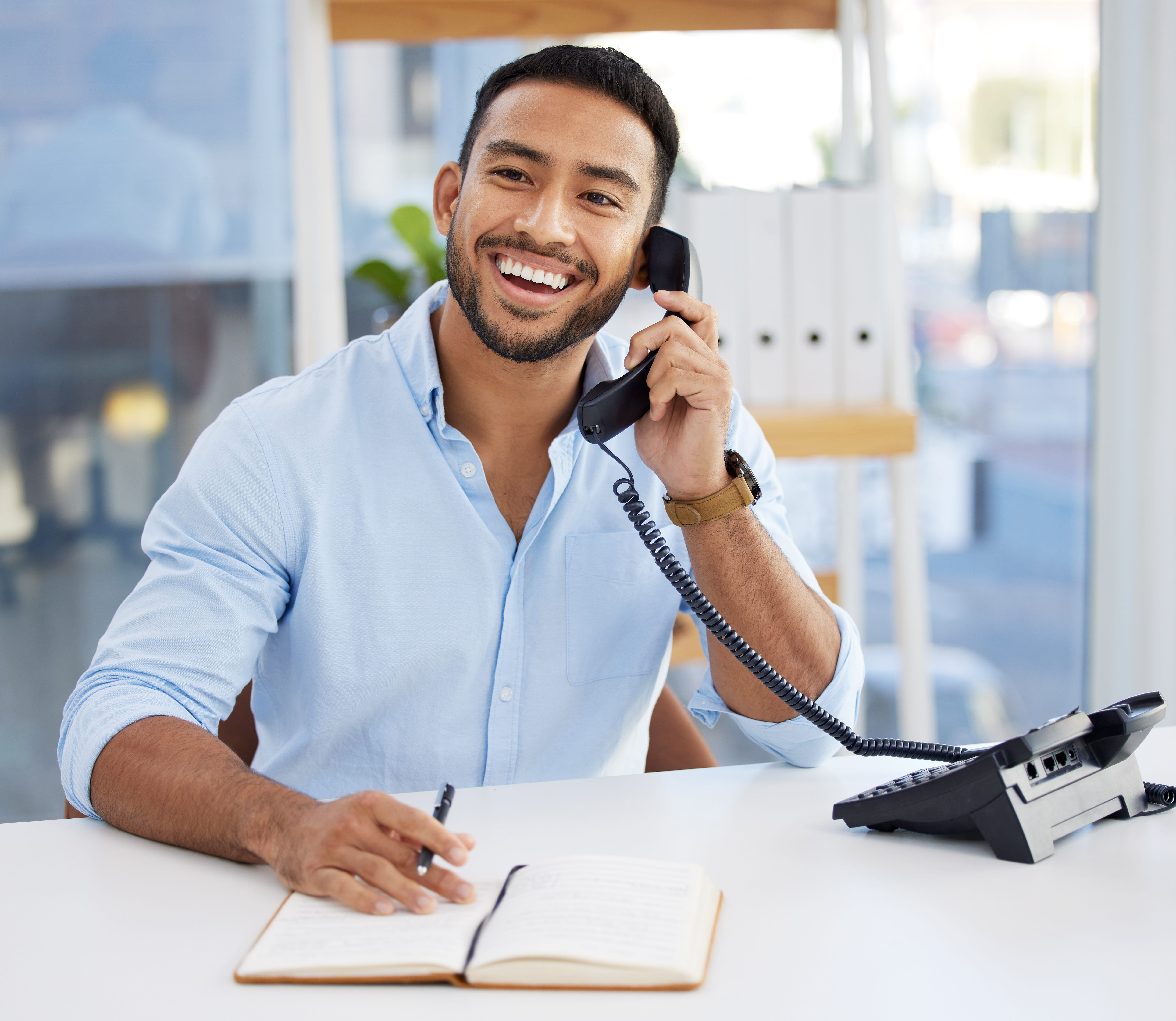 Young man smiling while answering calls on a landline phone