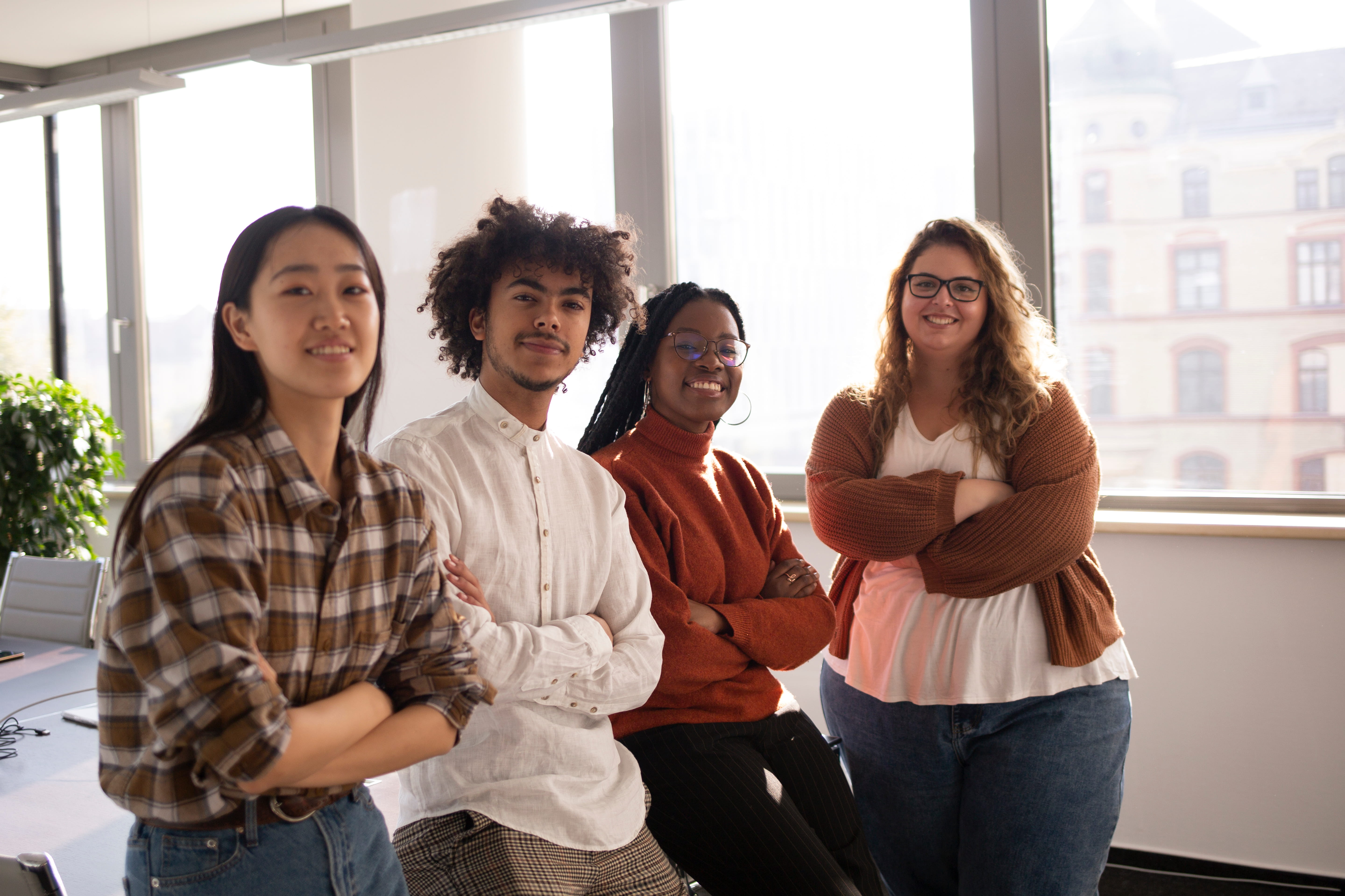 A group of four young colleagues in the office are looking at the camera