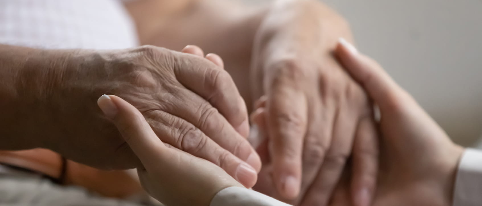 Close up kind caregiver medical worker holding hands of old retired patient