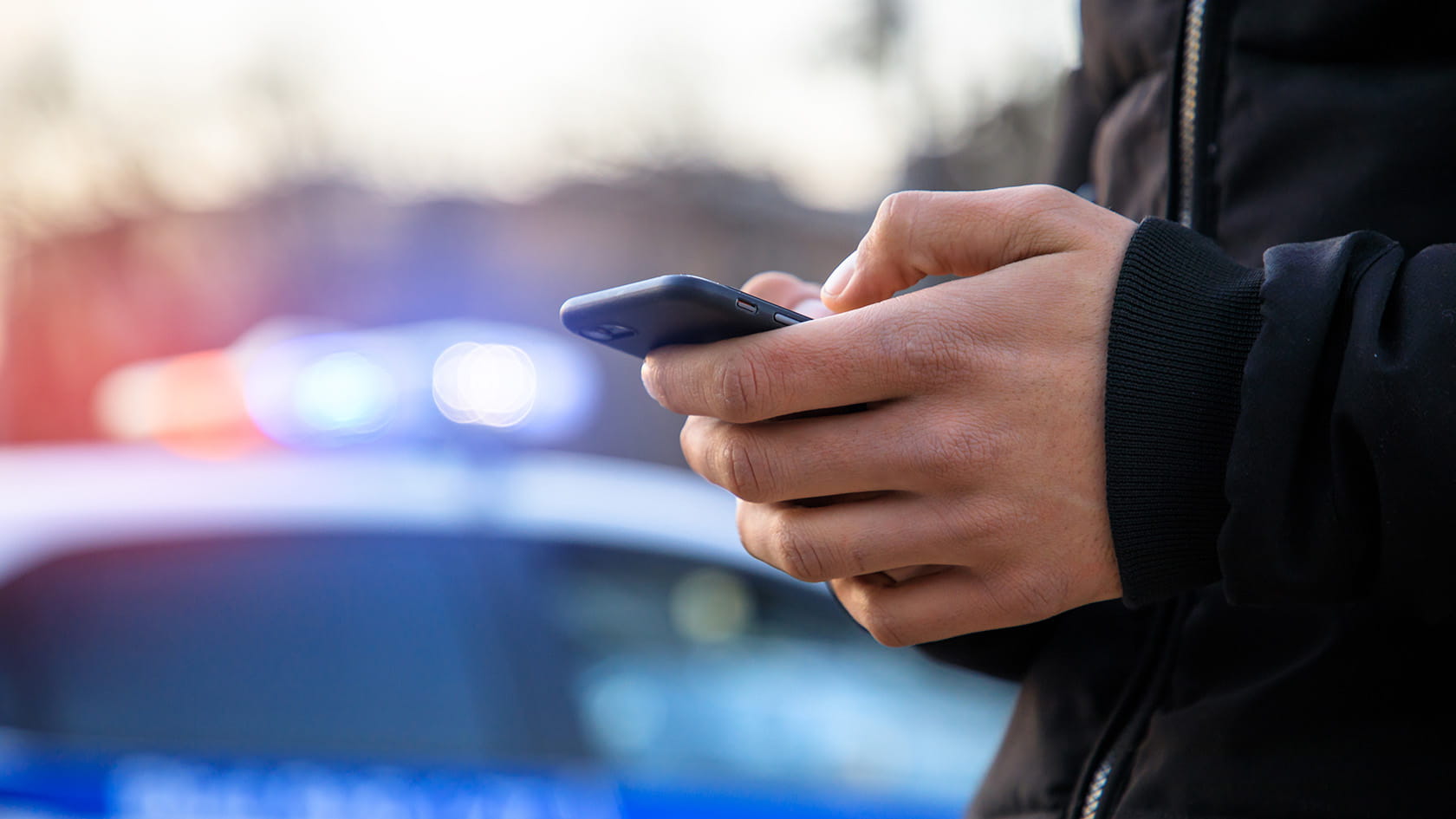 man holding phone with police in street