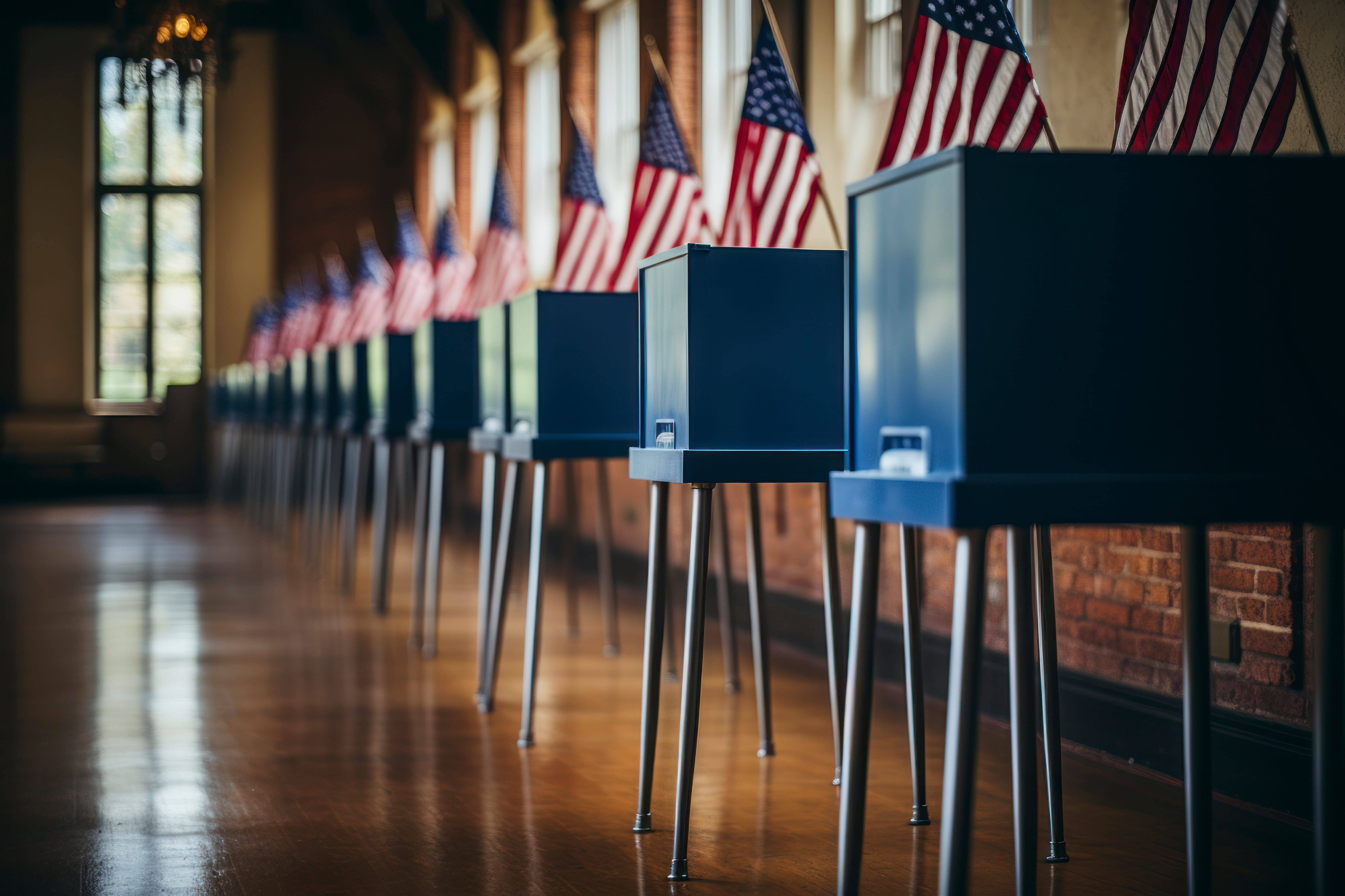 Straight on row of voting booths at polling station during American election. US flag in background.