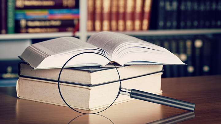 Magnifying glass and open books with turning pages on the table