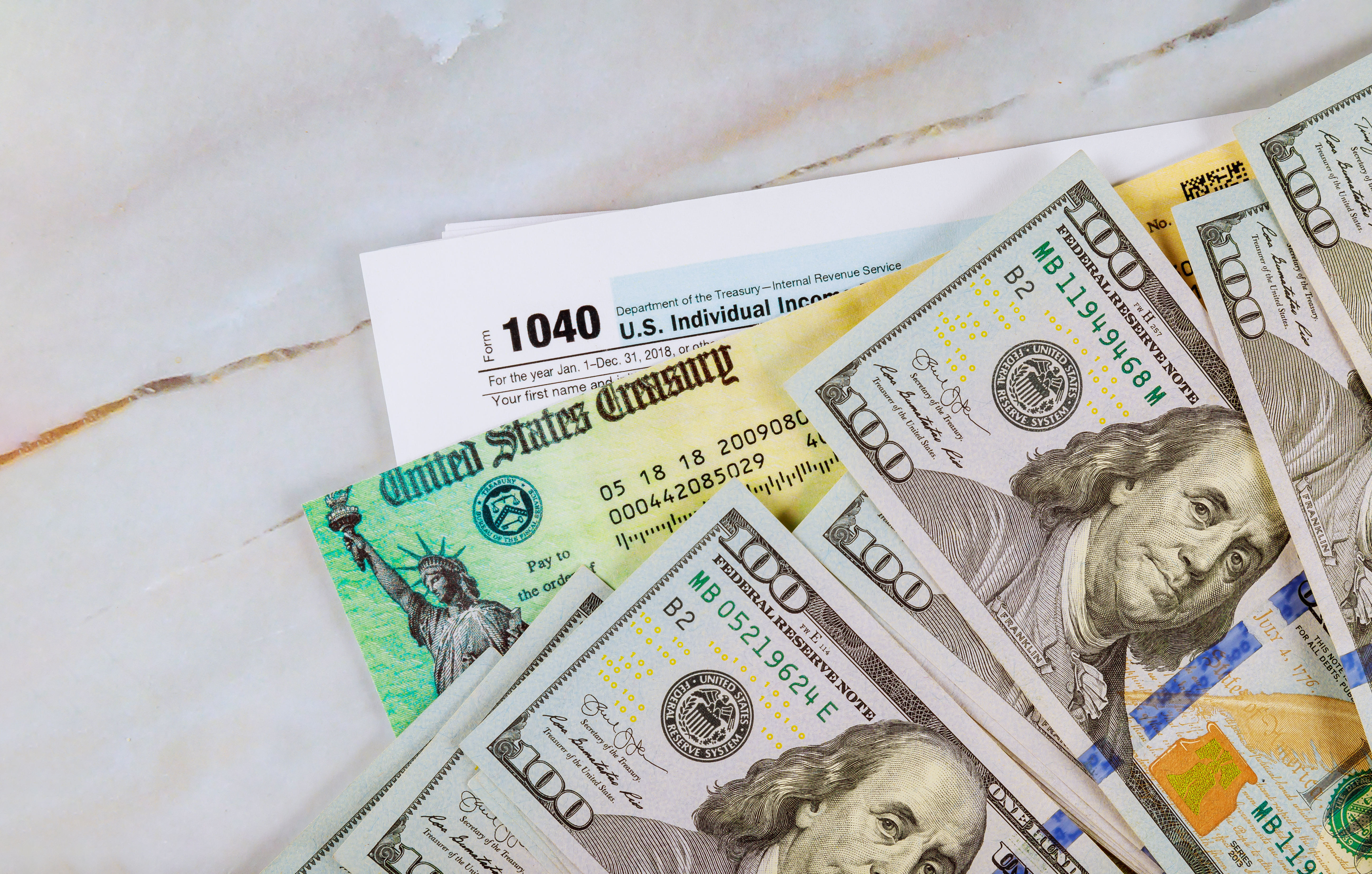 Stimulus economic tax return check and US 100 dollar bills currency.