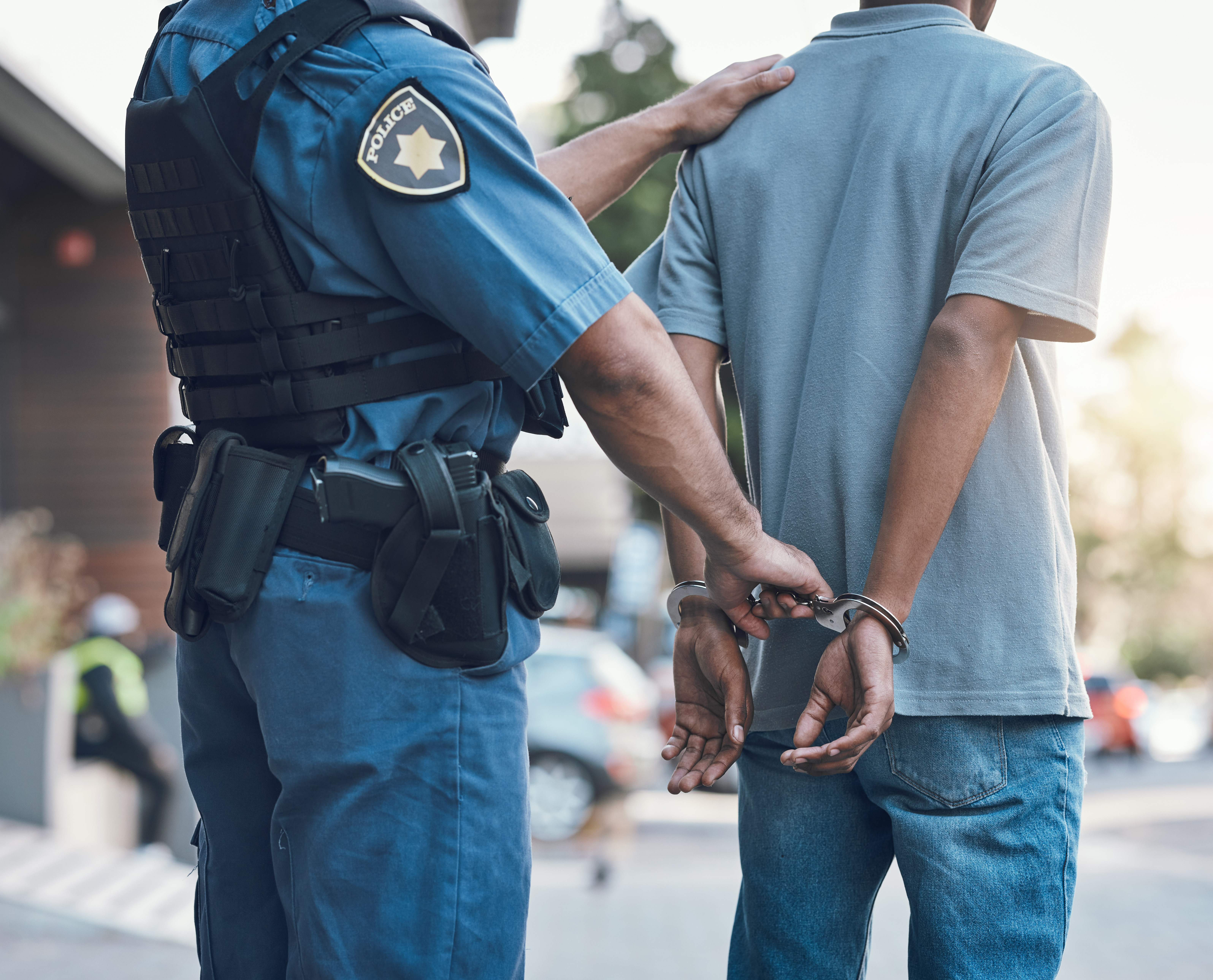 Stop, handcuffs and hands of police man with criminal in city for justice, crime or corruption. Illegal, arrest and law enforcement officer with suspect.