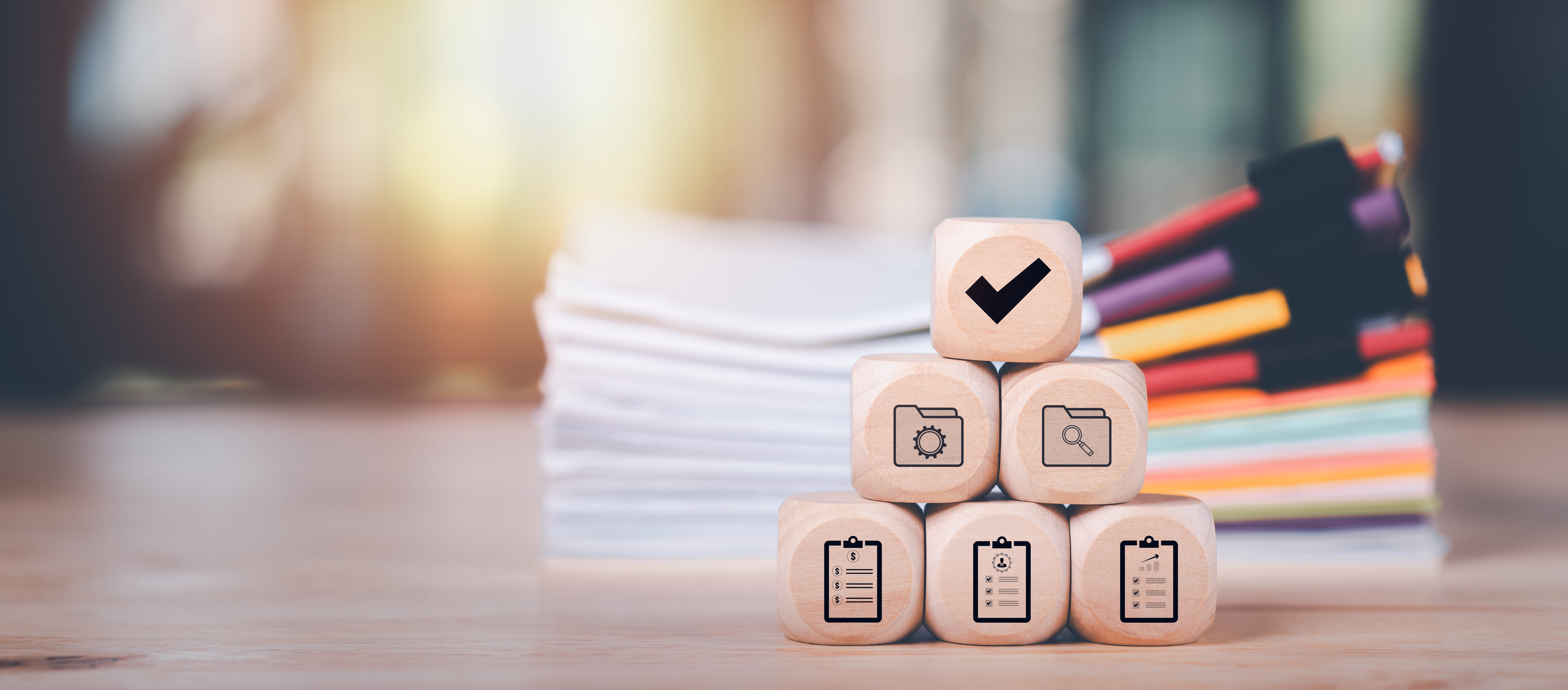 wooden blocks with icons showing auditing, evaluating quality, compliance, and laws