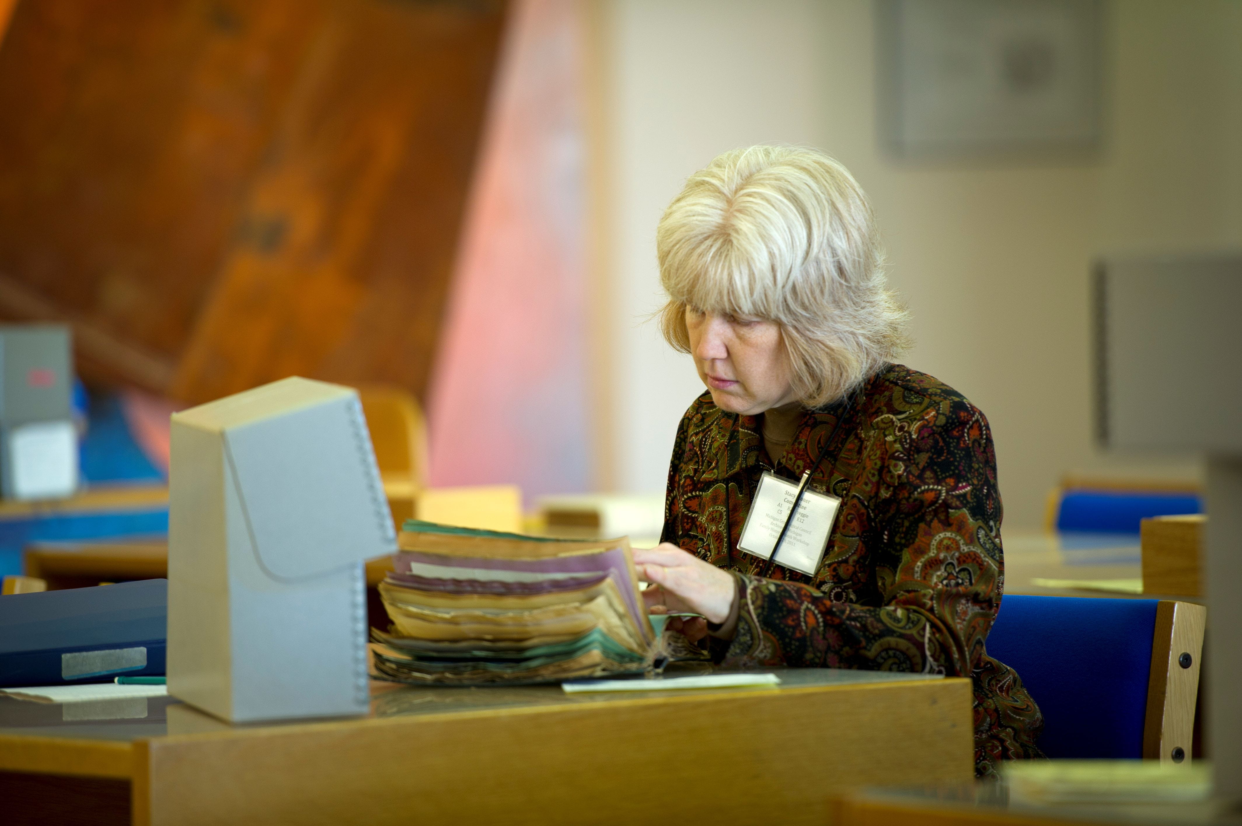 A women sitting at a table leafing through a volume.