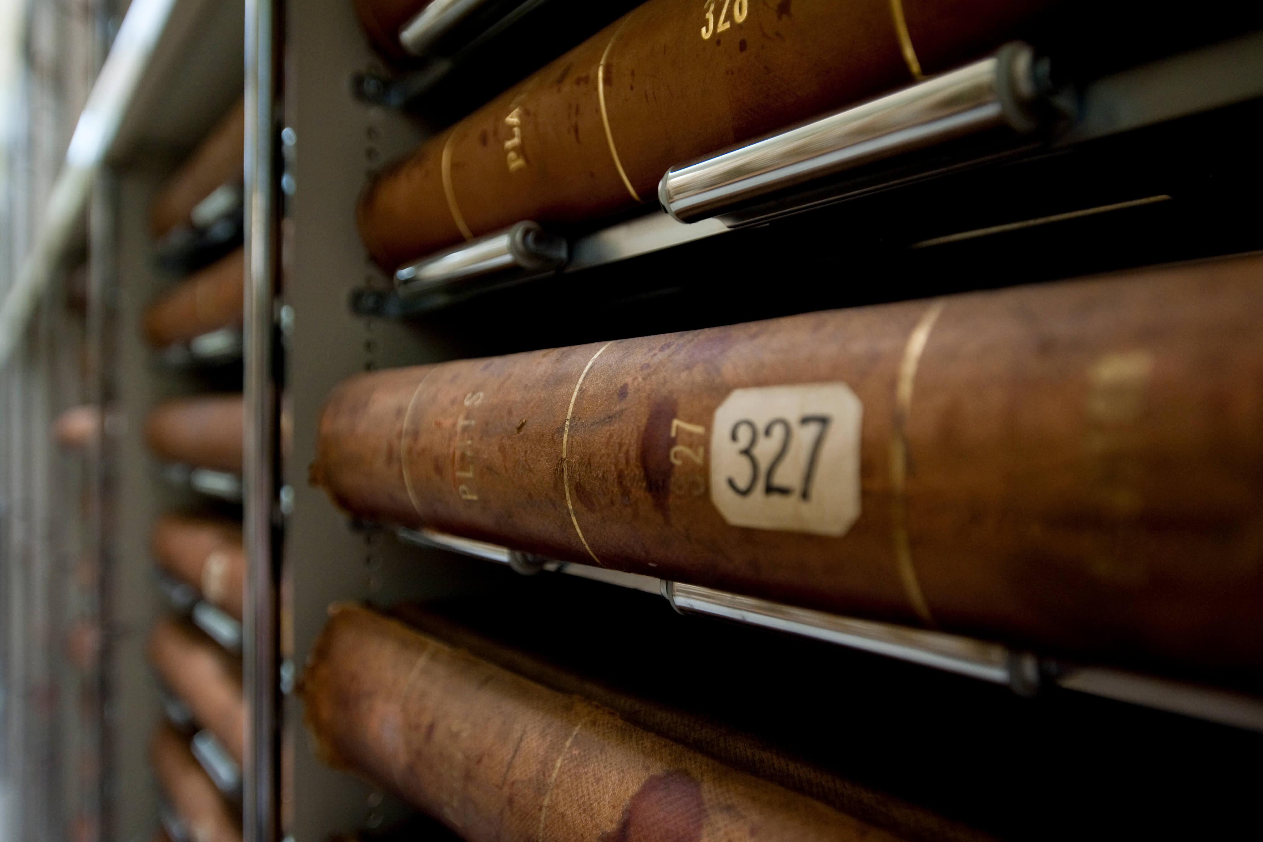 Volumes lying flat on metal shelfing that read "Auditor Plats."
