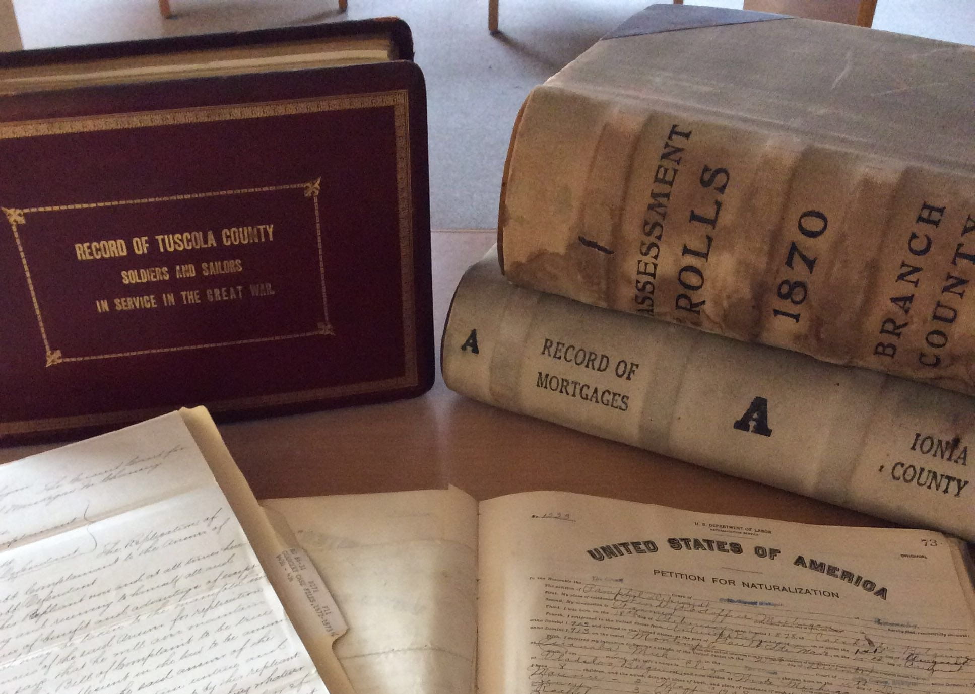 Volumes in the back and paper in the front highlighting a military census, an assessment, roll, and court documents.