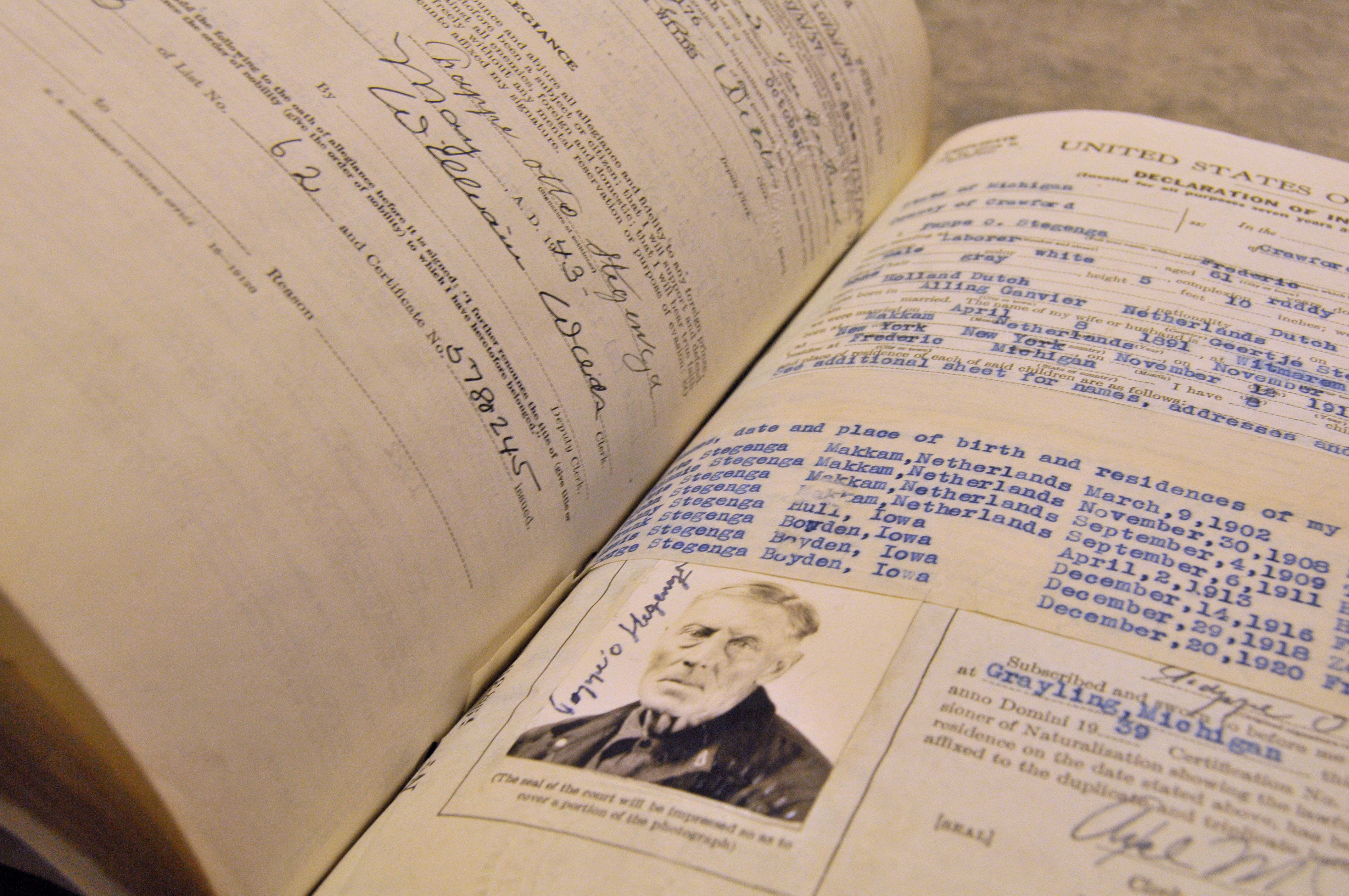An open volume of naturalization petitions. In the foreground is a picture of a man.