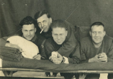Four men gathered across a gurney smiling.