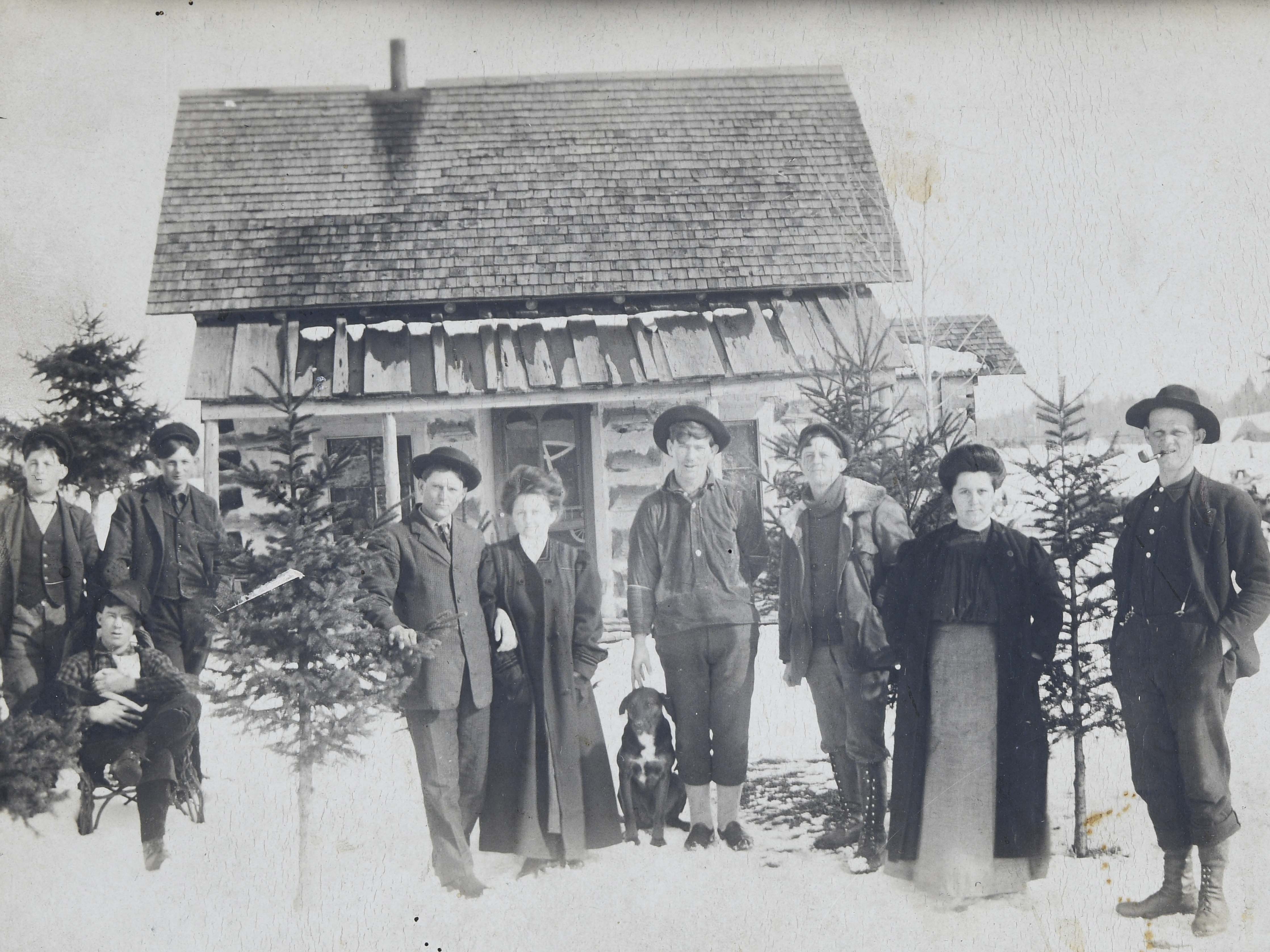 Family of nine posing outside their home in winter with their dog.