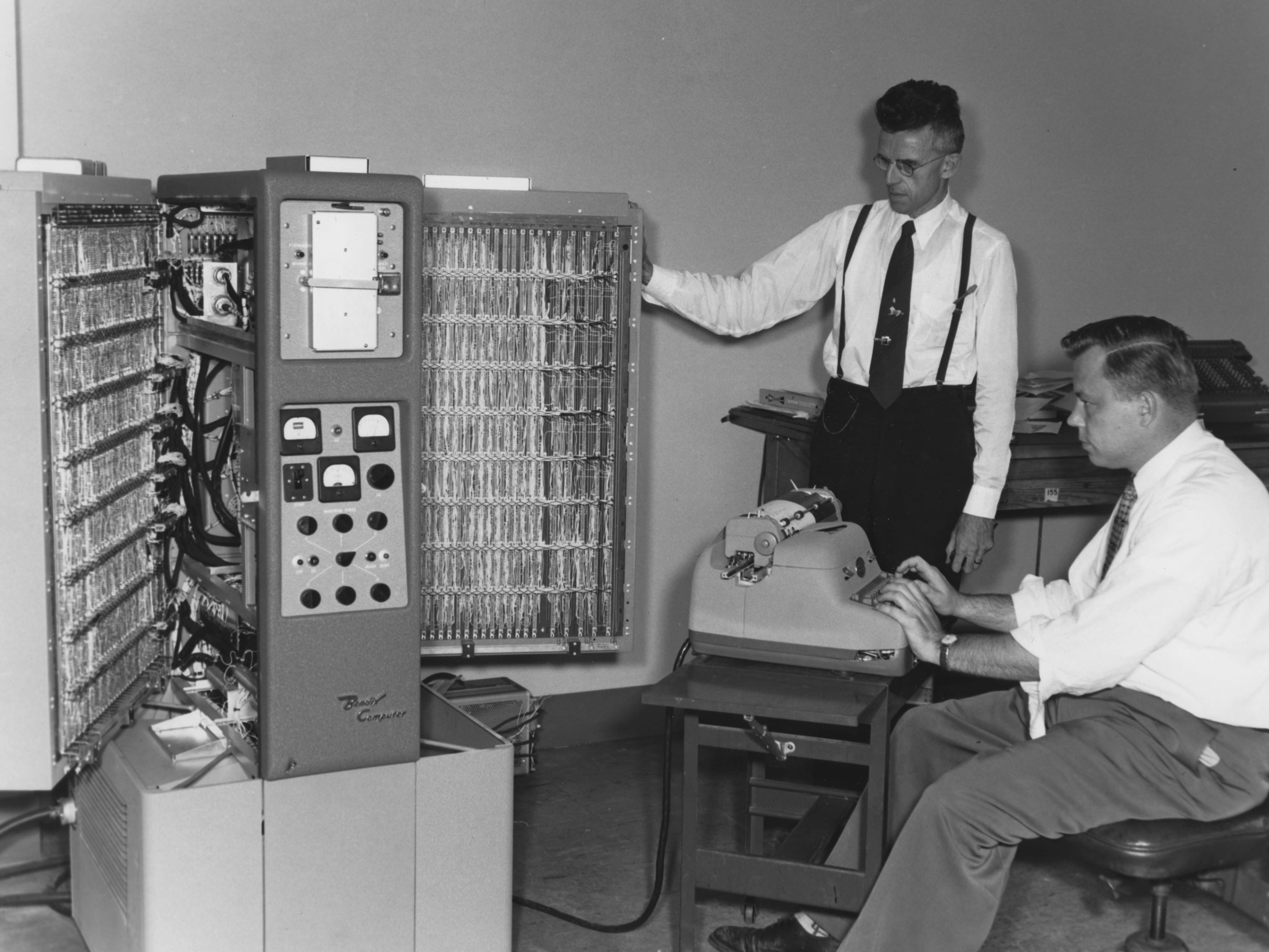 Two men working on a computer from the 1960s.