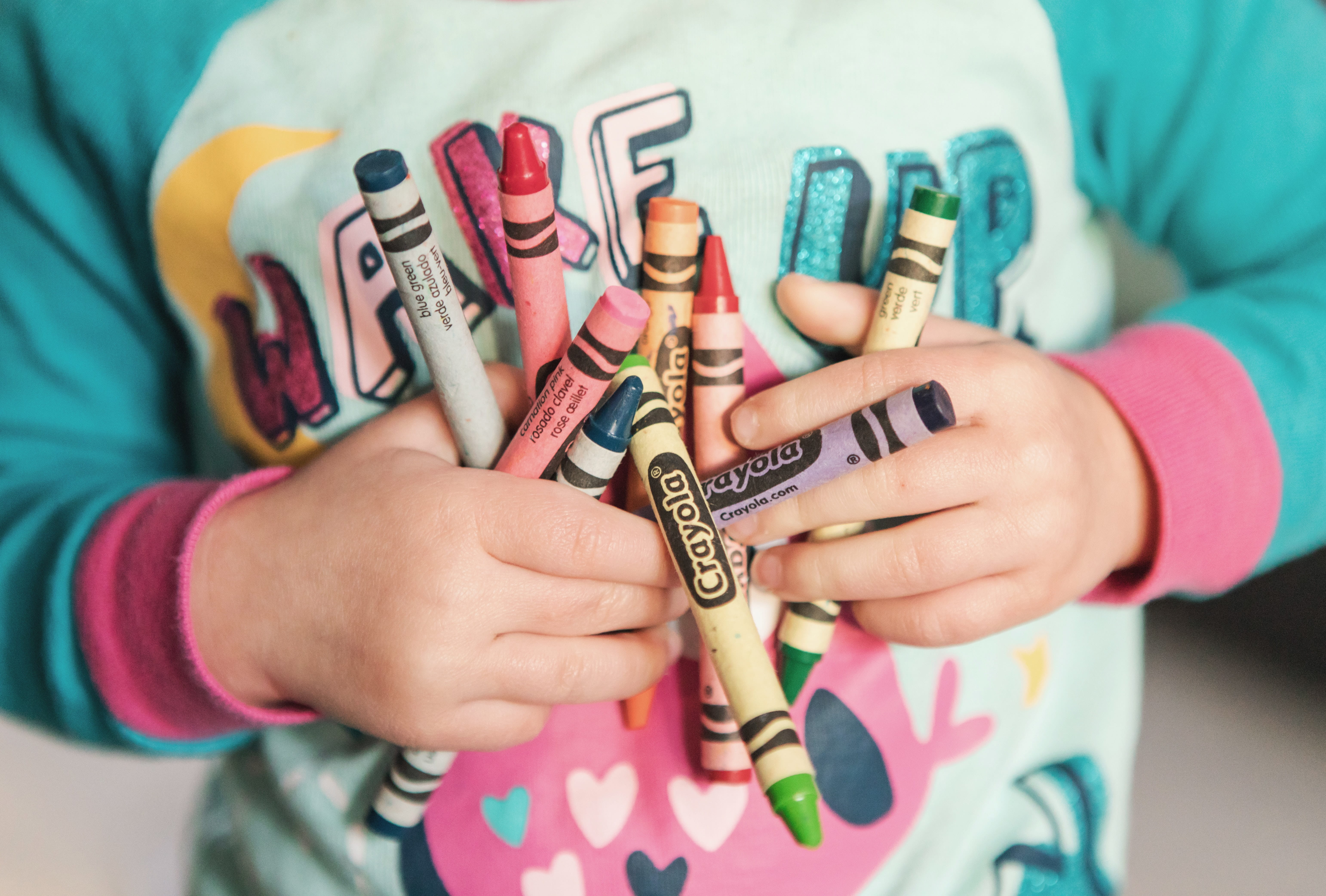 Image of a child holding crayons