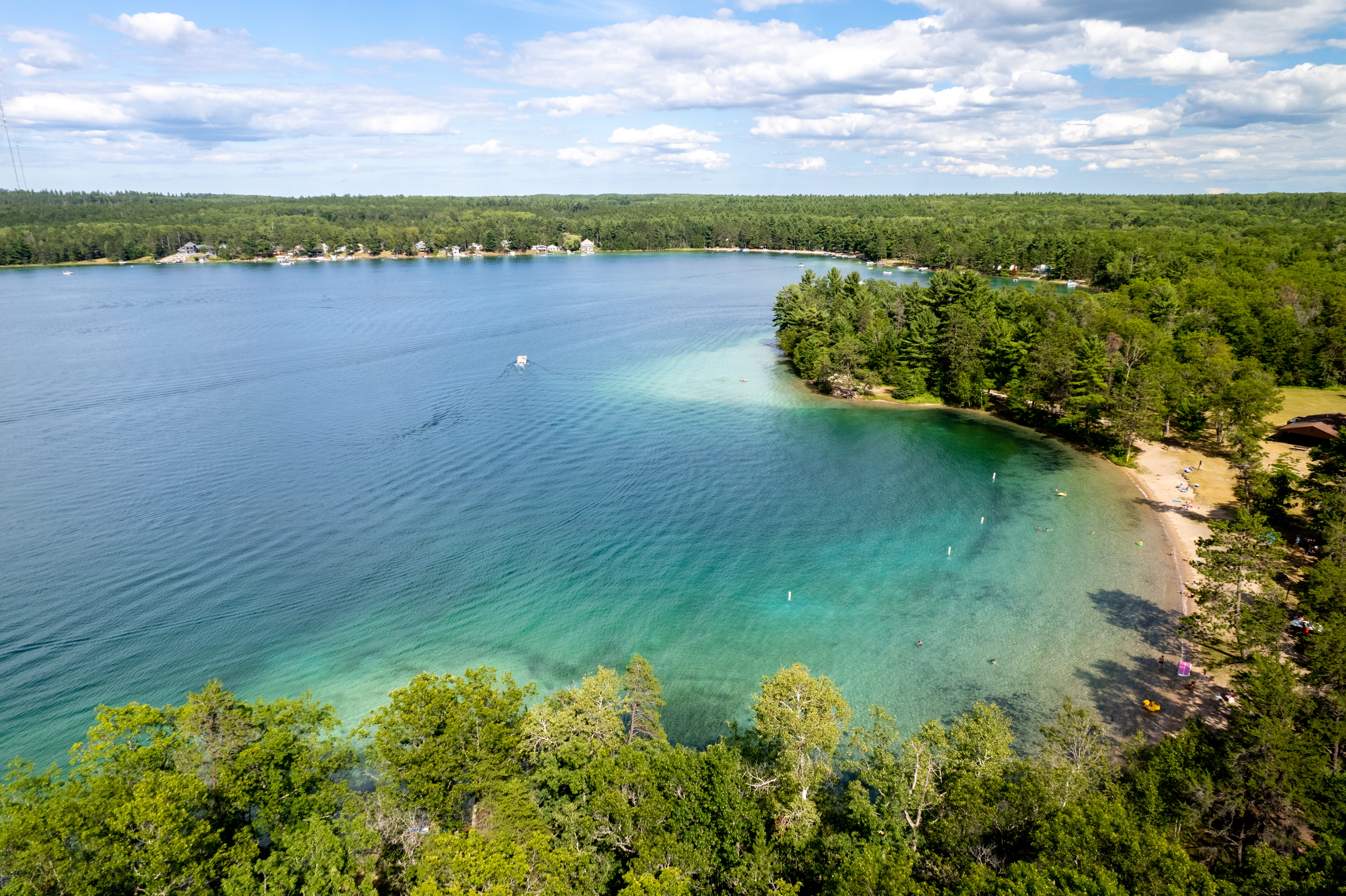 A clear blue lake surrounded by a forested green shoreline.