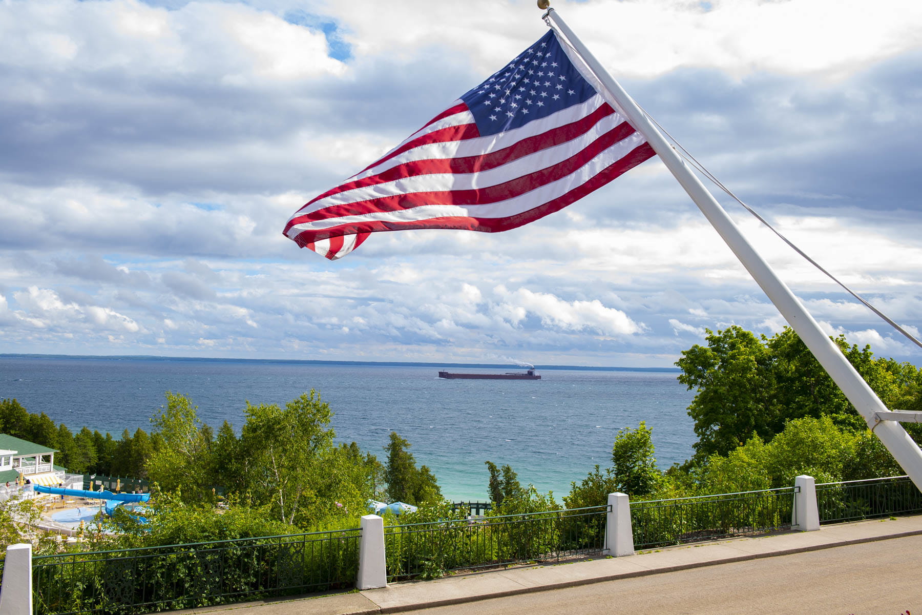 An American flag overlooking a hilly landscape and lake.