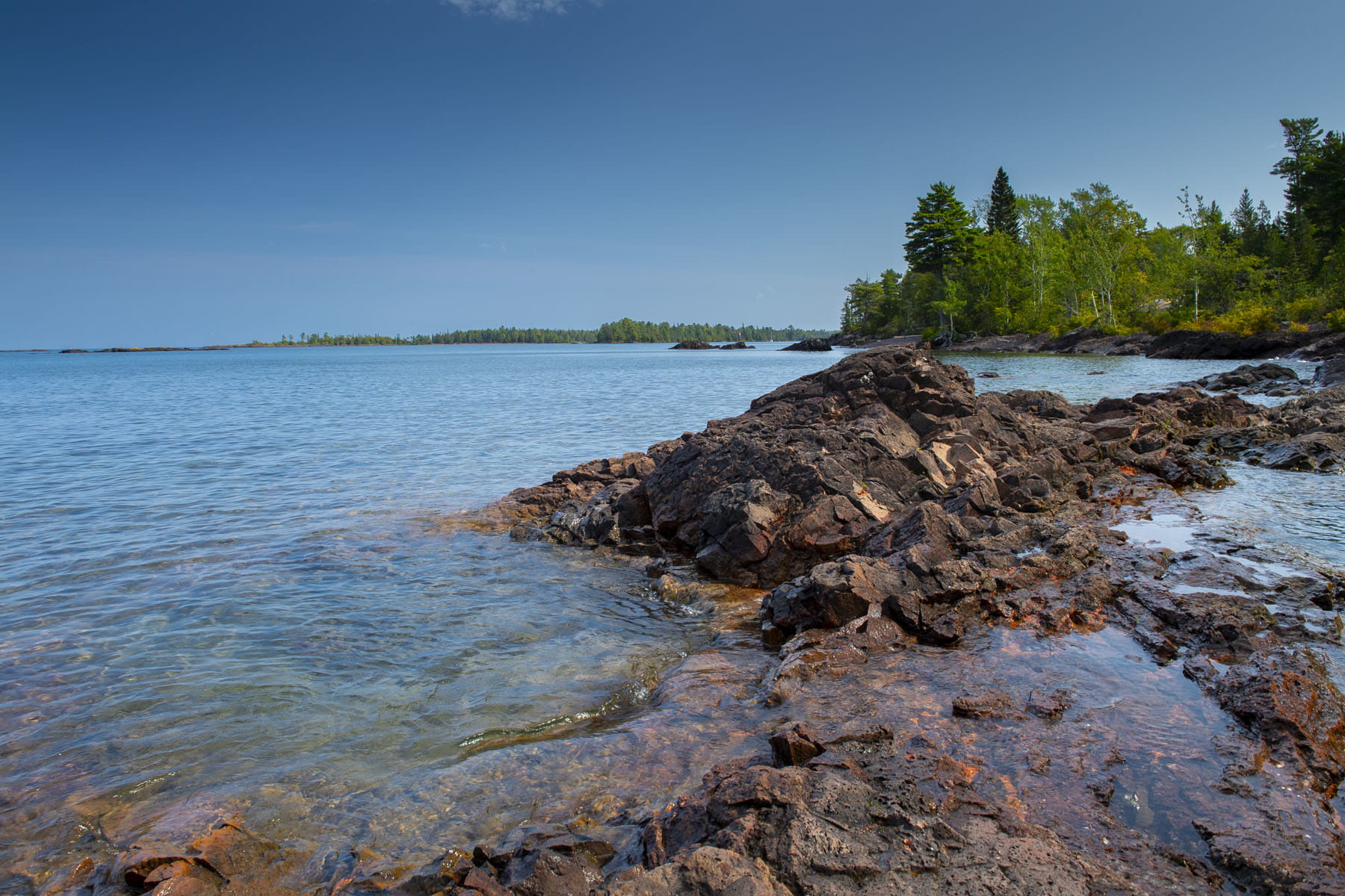 Deep blue waters stretching out from a crisp shoreline.