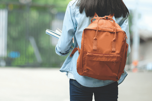 Student with backpack holding books