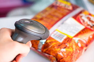 Person holding a scanner against a bag of chips to get the price.