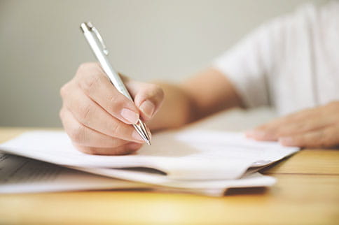 Person using a pen to fill out a paper application