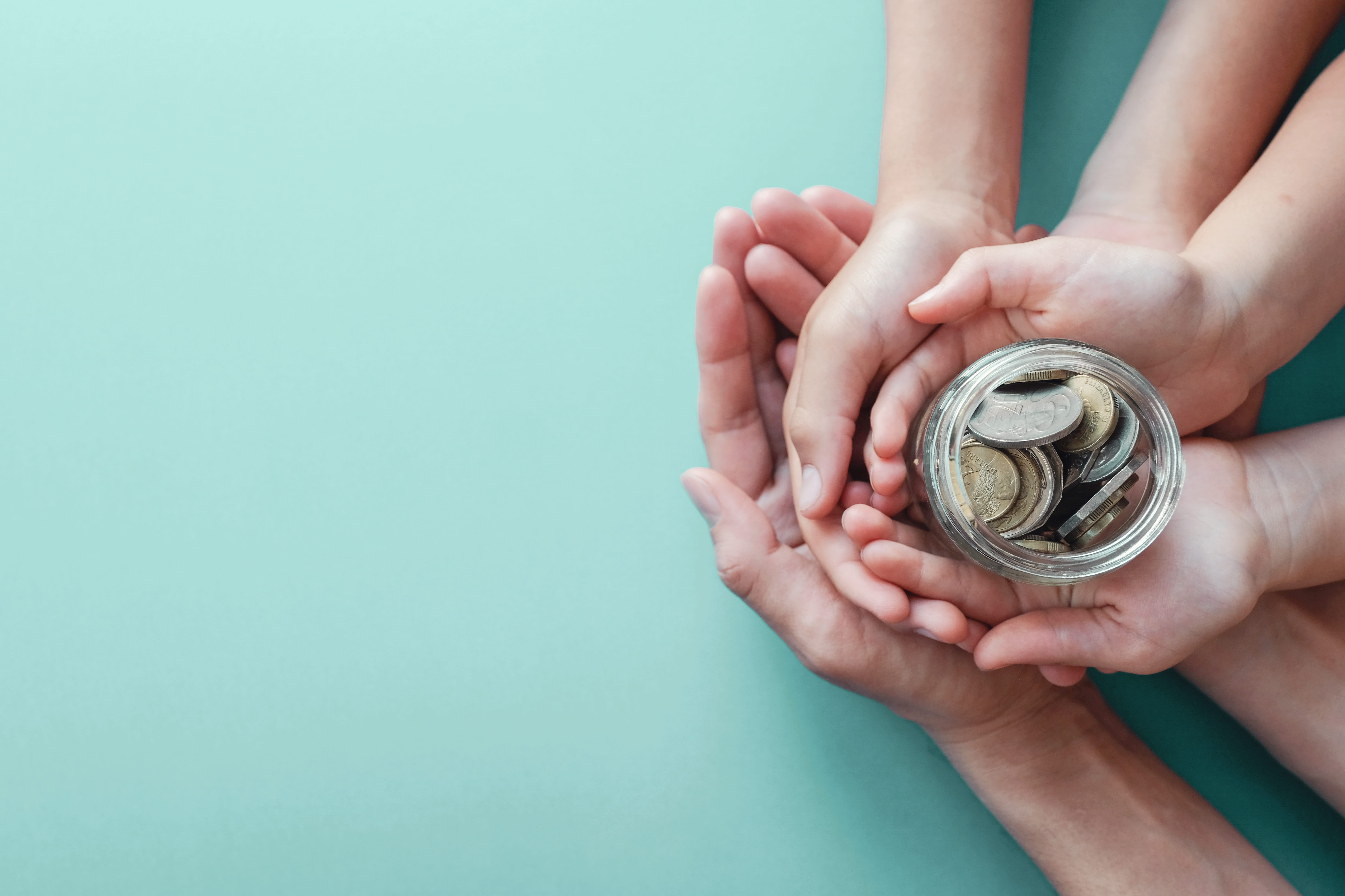 child and adult holding money jar, donation