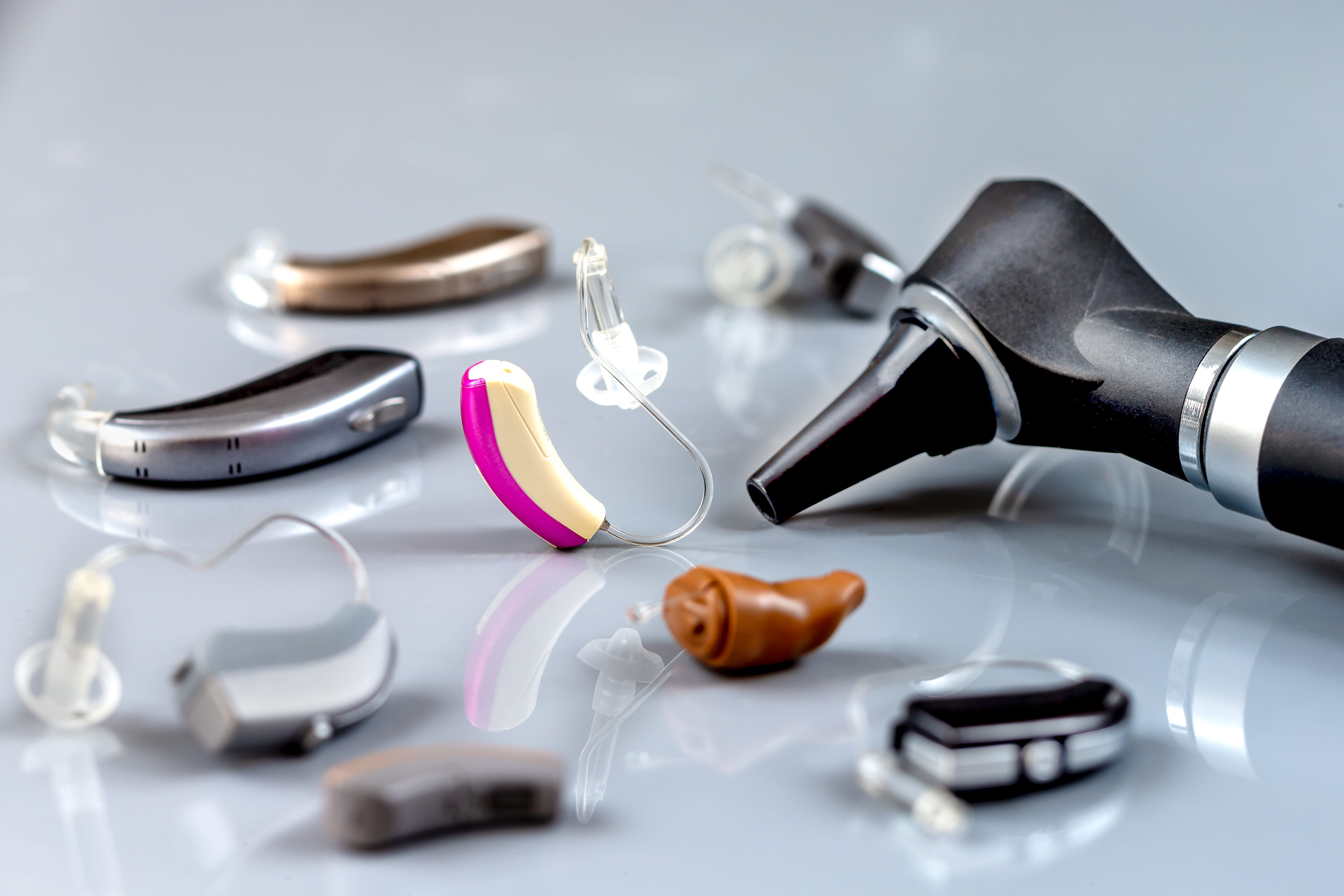 Multiple versions of hearing aids laid on a gray table