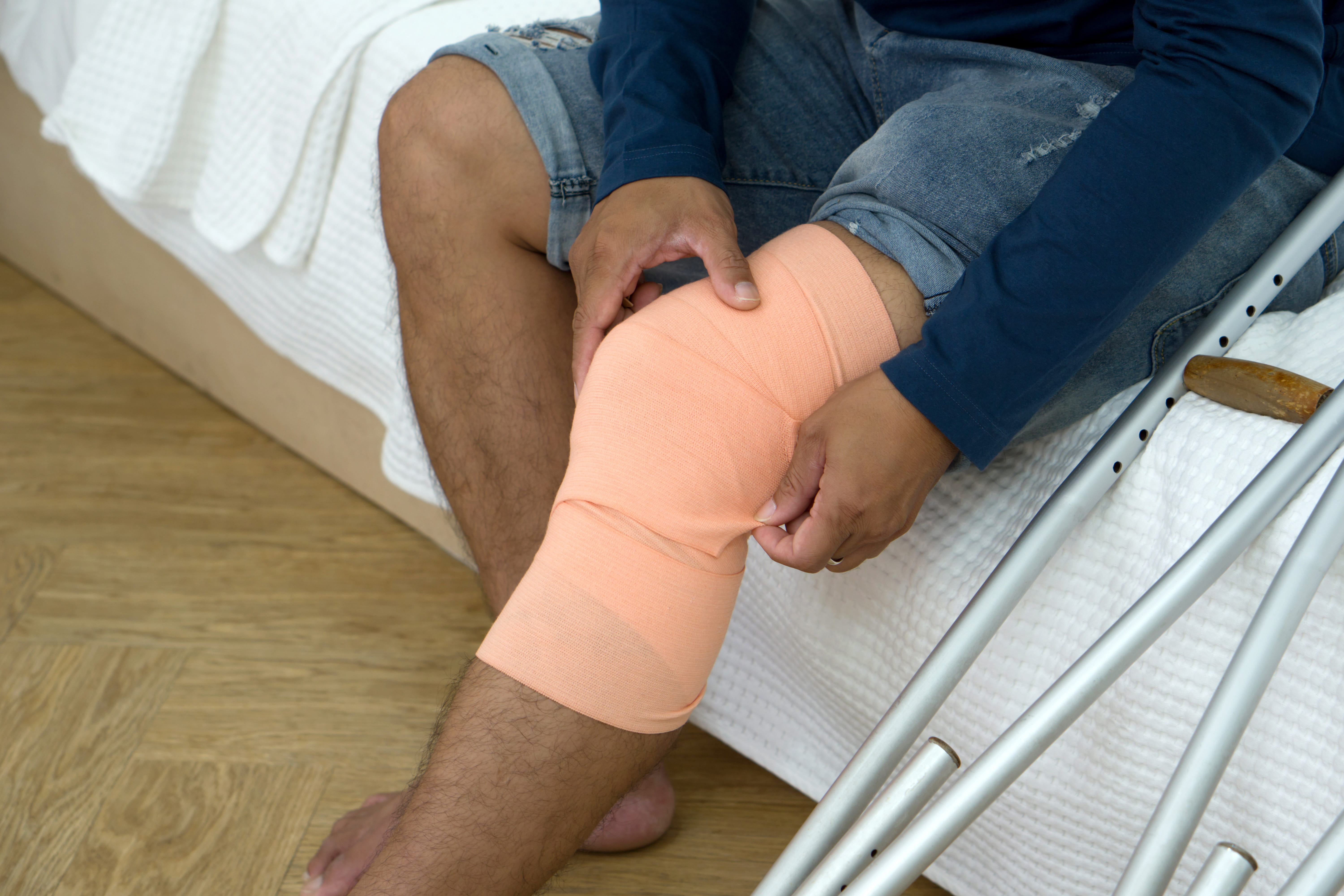 A man with a broken knee sitting on his bed
