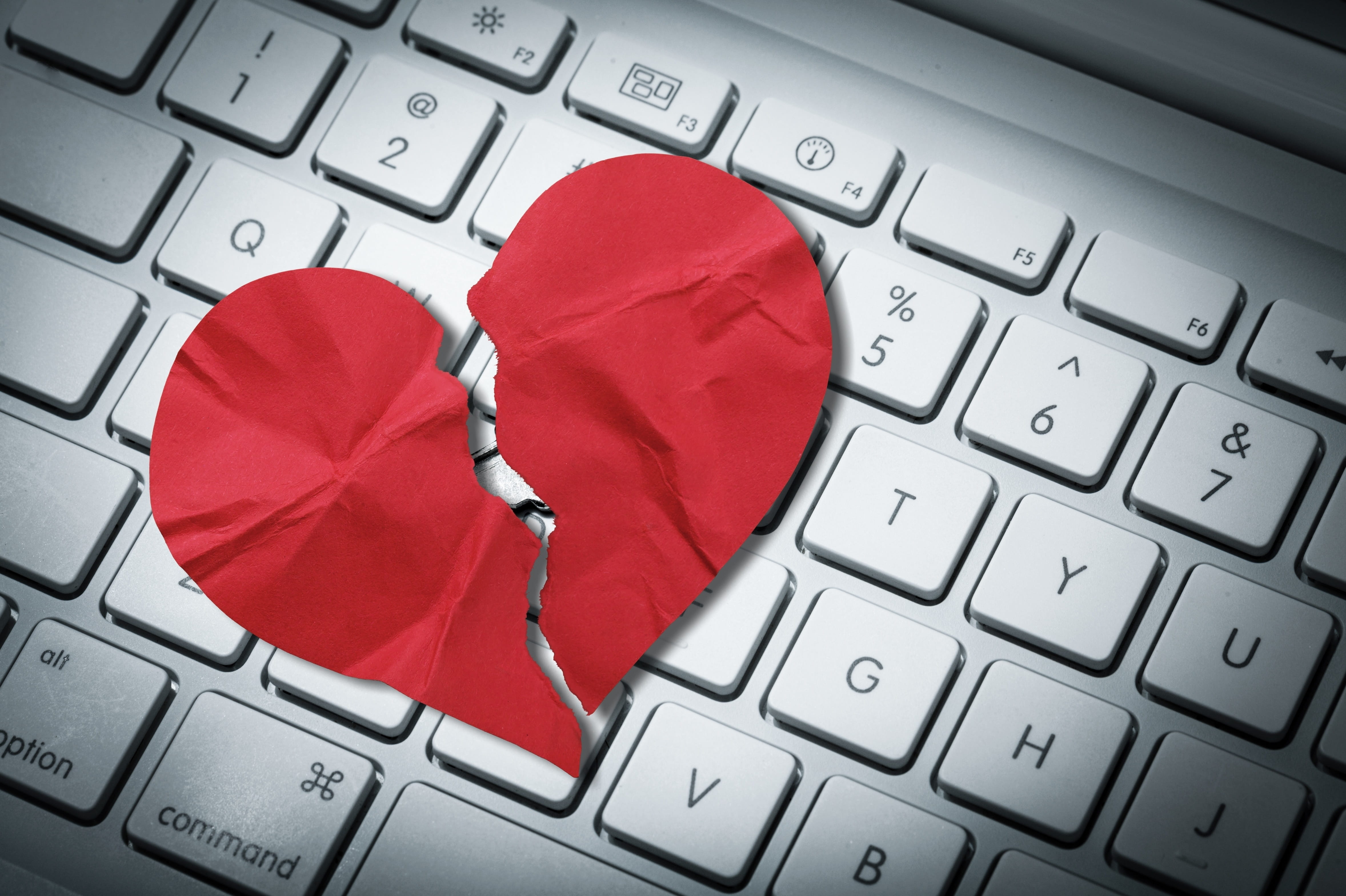 Red broken heart paper on keyboard computer background