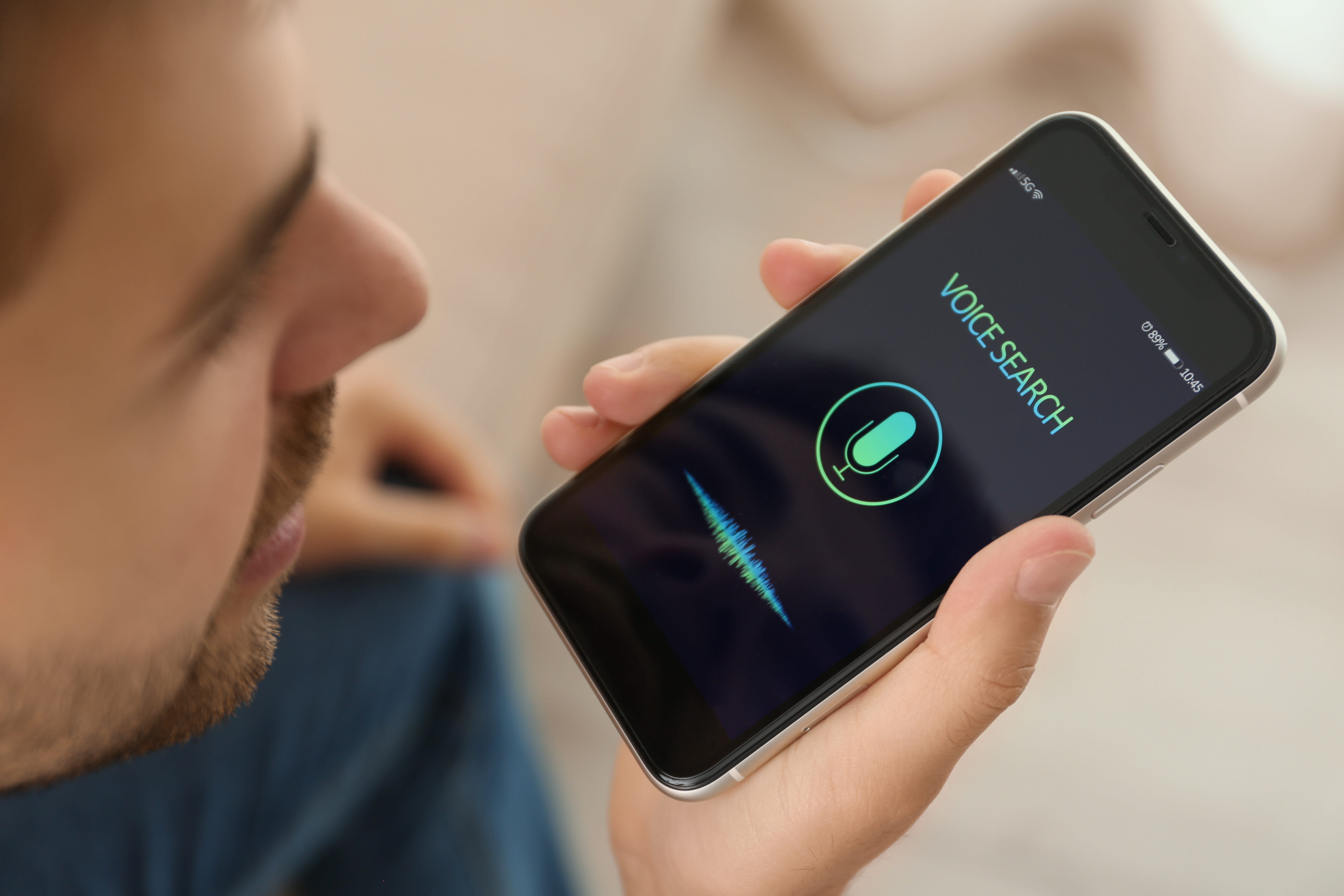 Young man using voice search on smartphone indoors