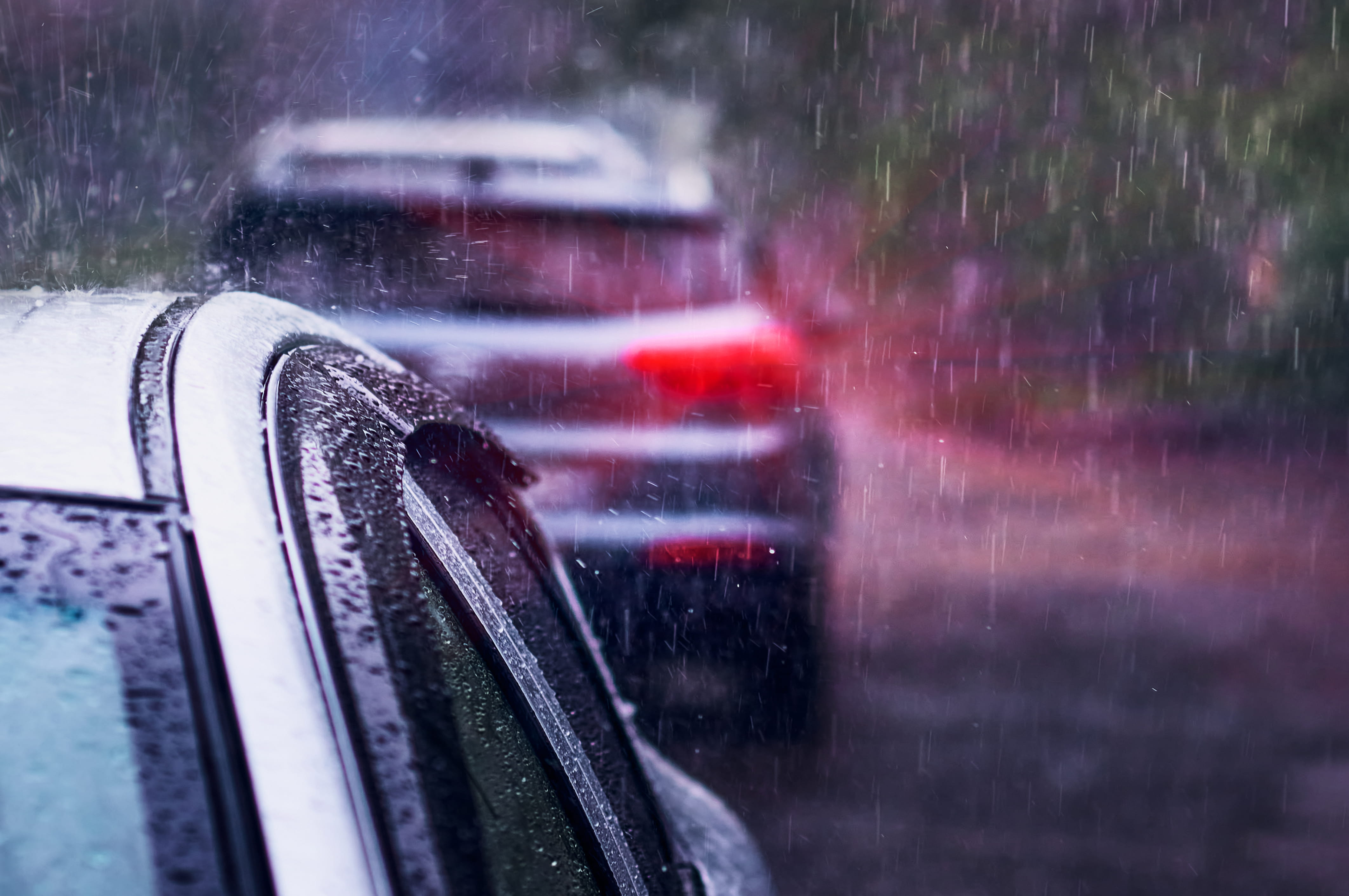 Heavy rain falls on the roof of a car during a thunderstorm