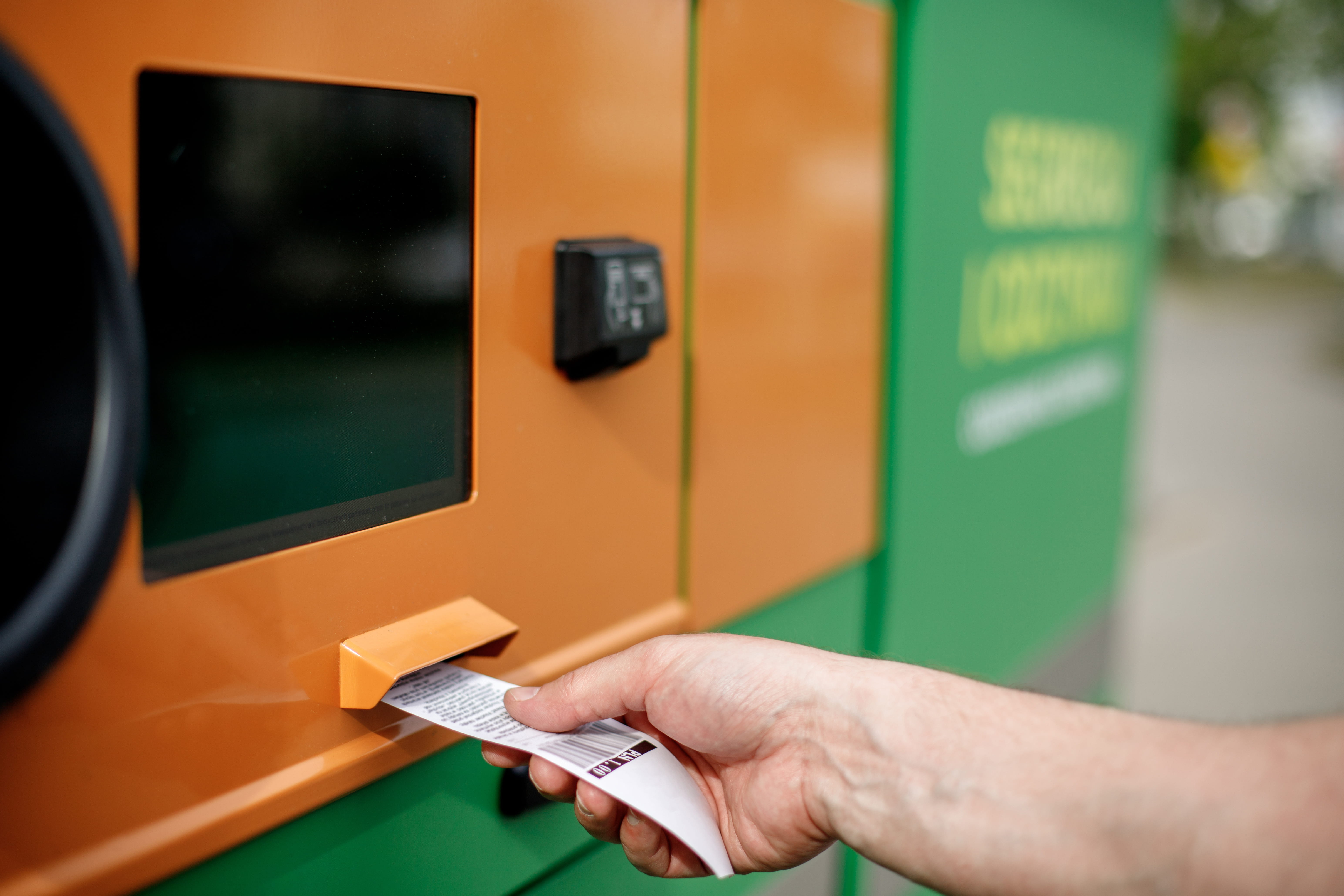 Man hand puts plastic bottle to the bottle recycling machine.
