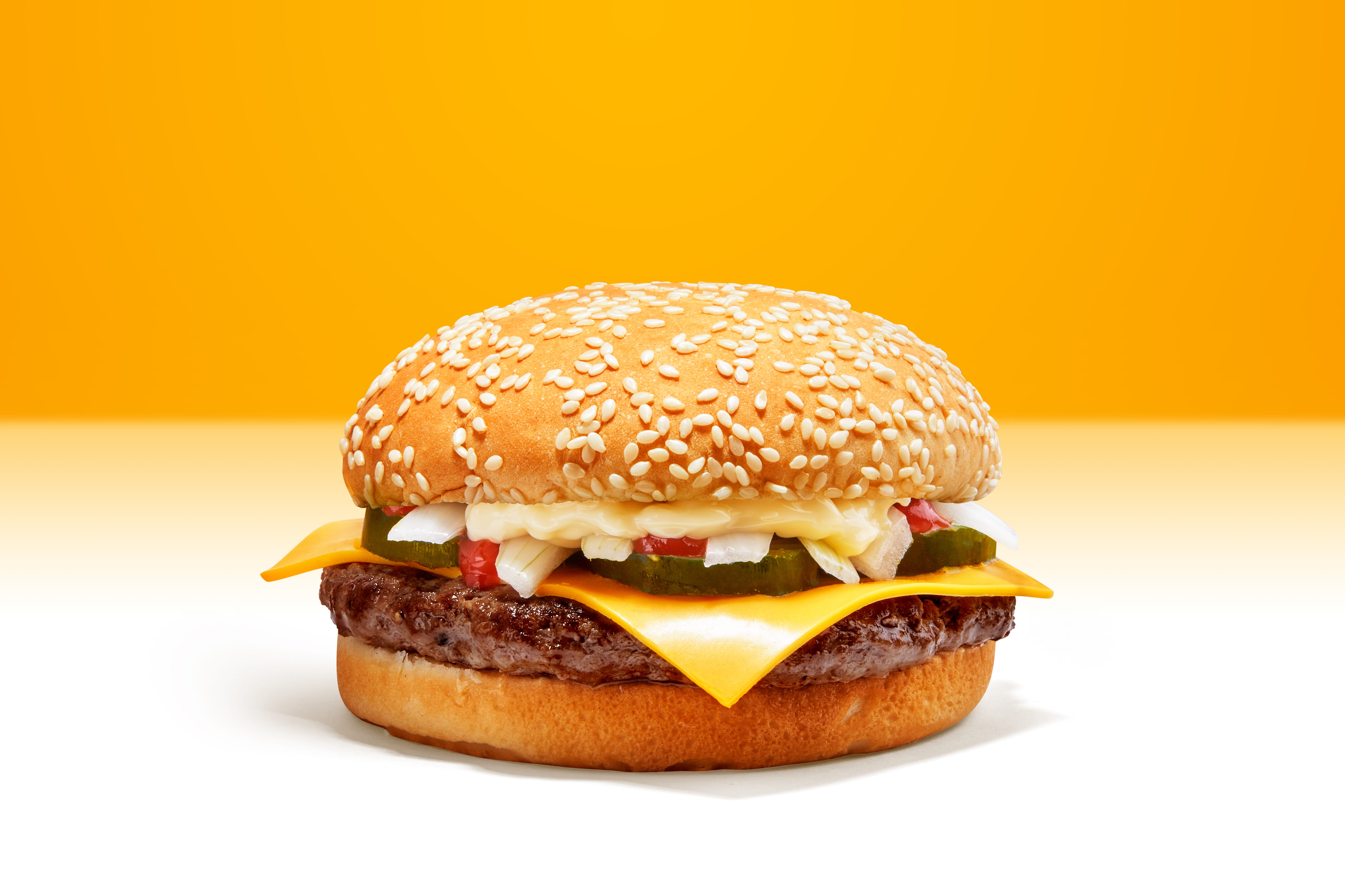 Cheese Beef Burger consists of Bun Bread, Patty, Pickle, Onion, Mayonaisse, Ketchup and Cheddar Cheese in a yellow background