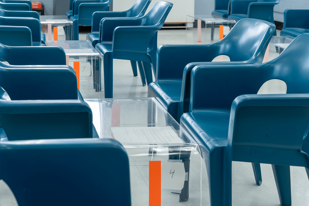 Organized rows of tables and chairs in a prison visiting area.