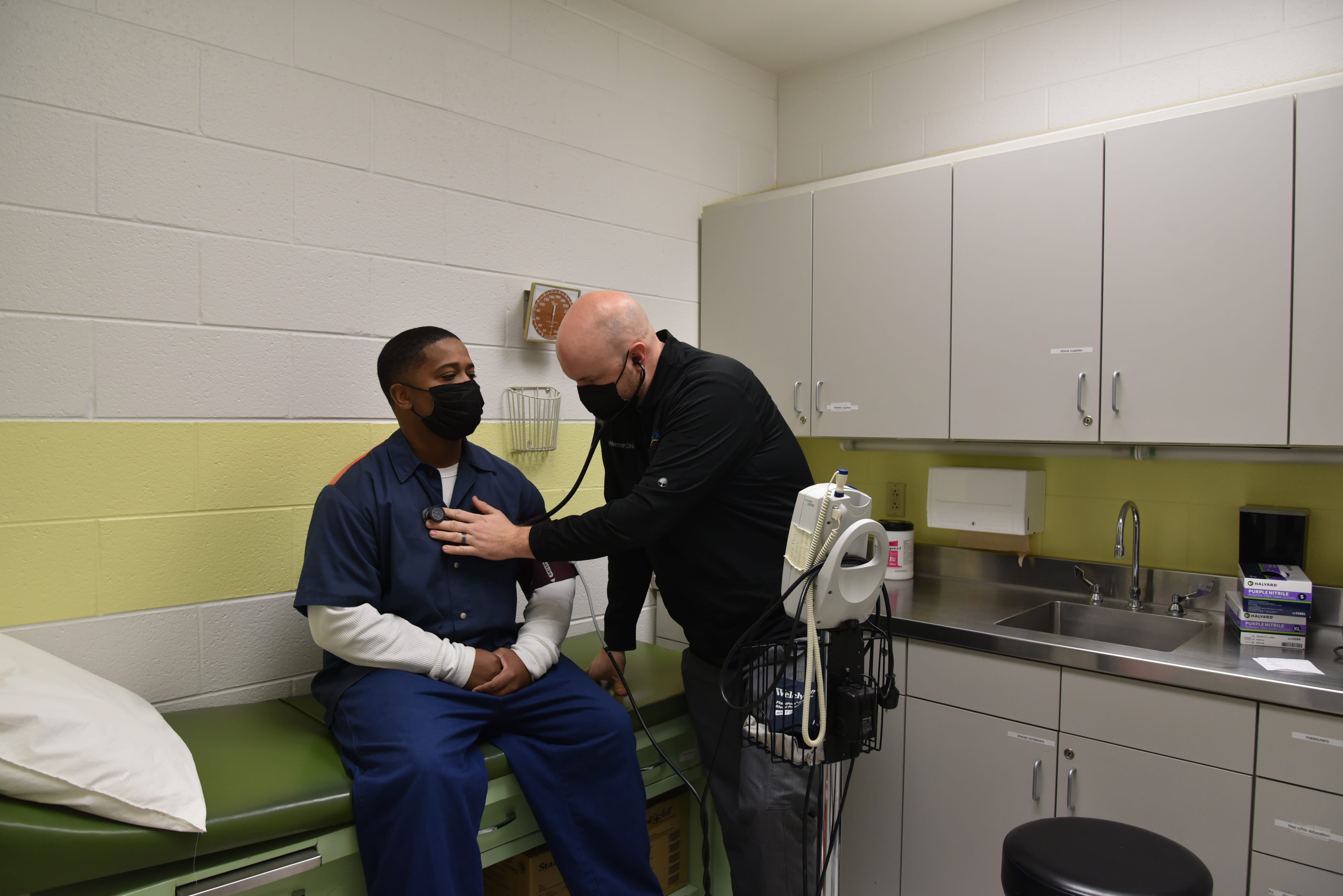 Doctor examining a prisoner in patient exam room 