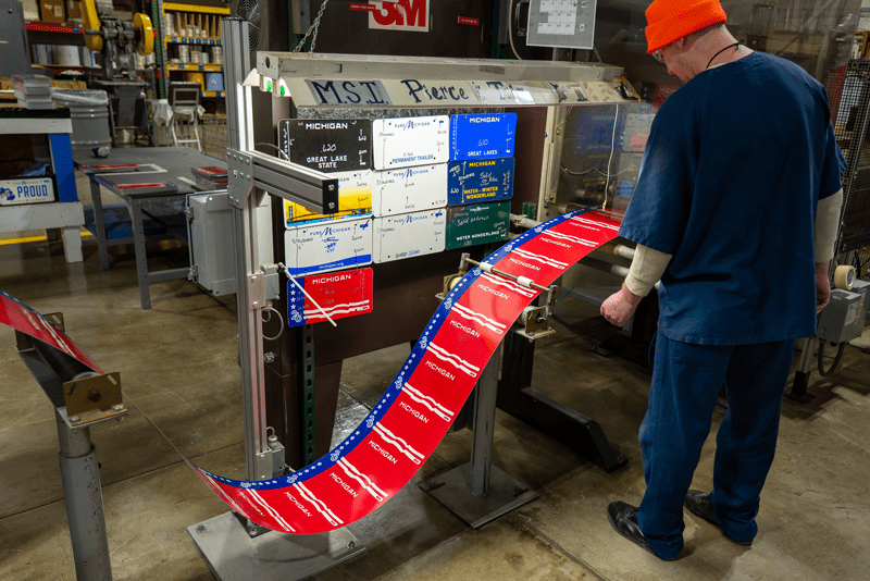 A prisoner operating a license plate stamping machine.
