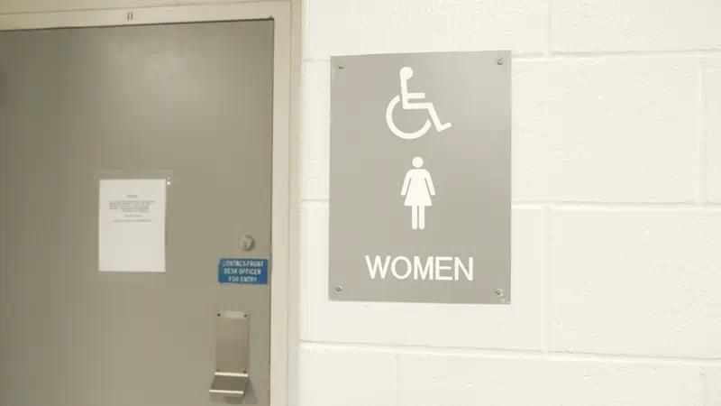 A door to a women's restroom with the bathroom sign next to the side of the door.