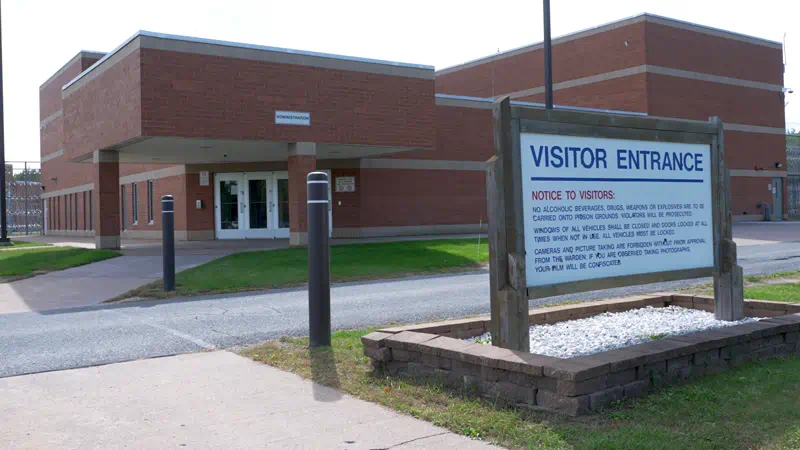 The main entrance to a large building made of brick with pathways and a sign that reads "Visitor Entrance" in front of the building.