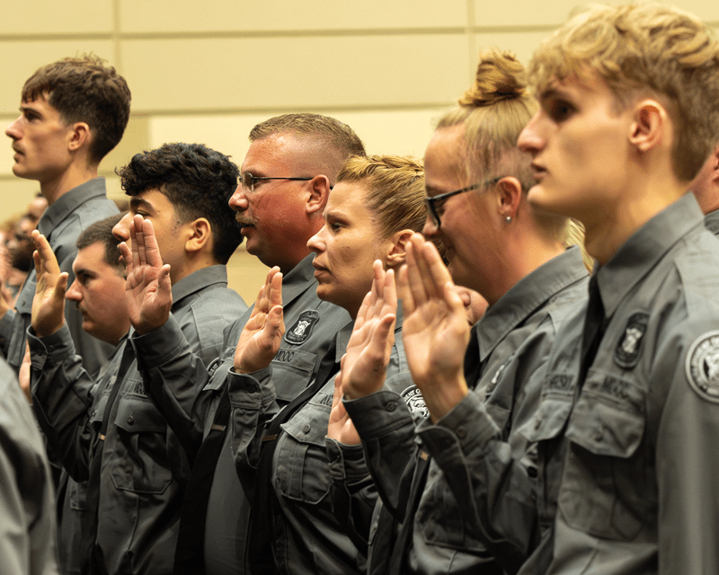 New corrections officers giving their oath during a graduation ceremony.
