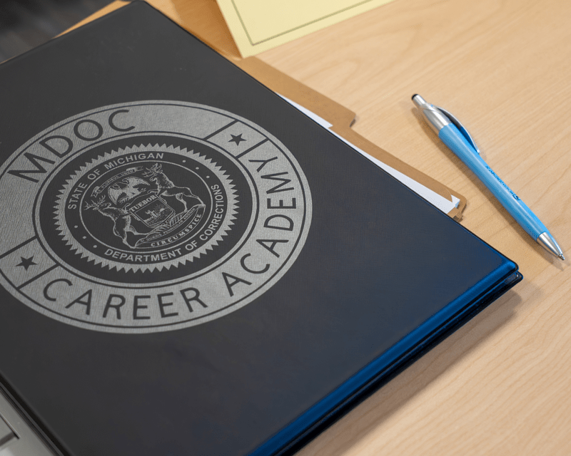 A dark folder with MDOC Career Academy written on top.
