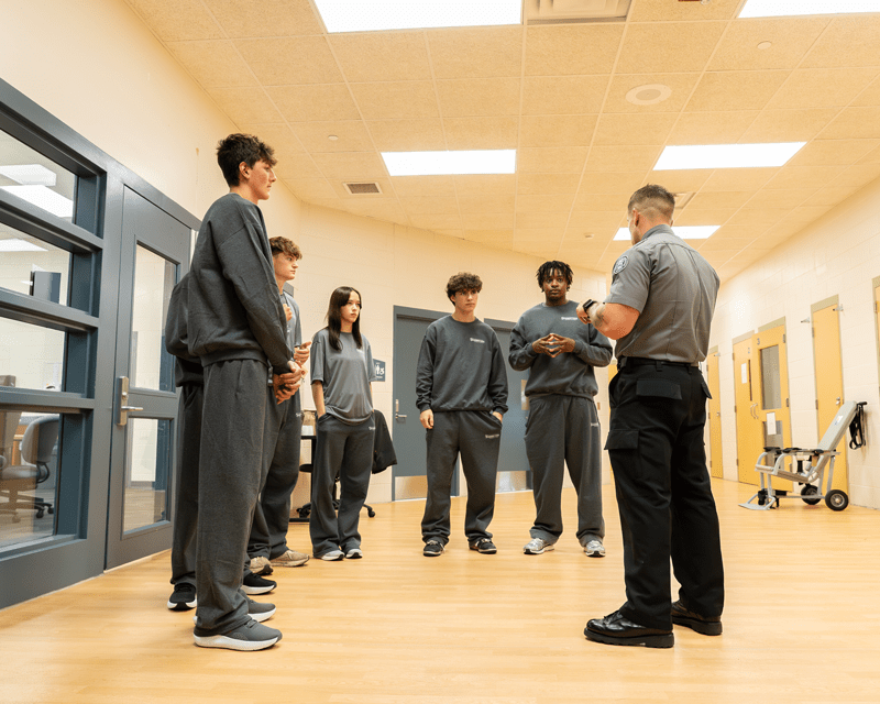 A group of male and female students wearing sweatsuits standing in a circle.