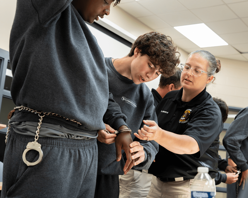A student practicing how to properly handcuff a person during a training session.