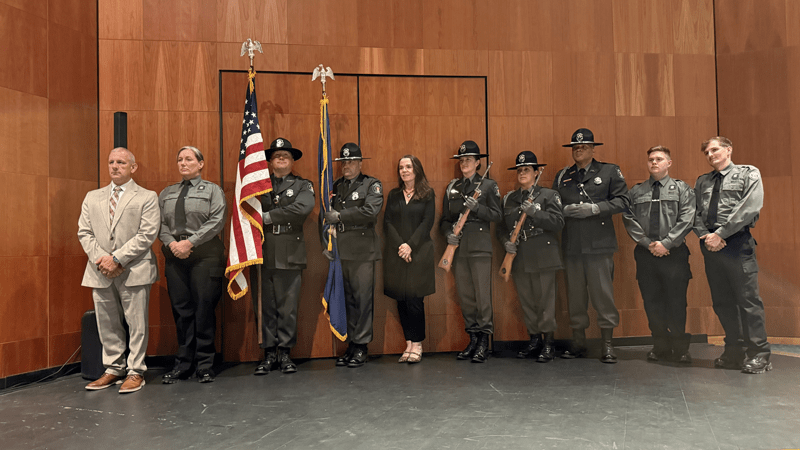 New corrections officer recruits stand amongst the Michigan Department of Corrections Honor Guard.