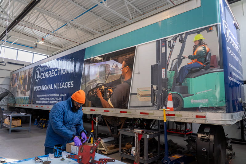 A semi-truck trailer with graphics and text promoting Michigan Department of Corrections' Vocational Villages.