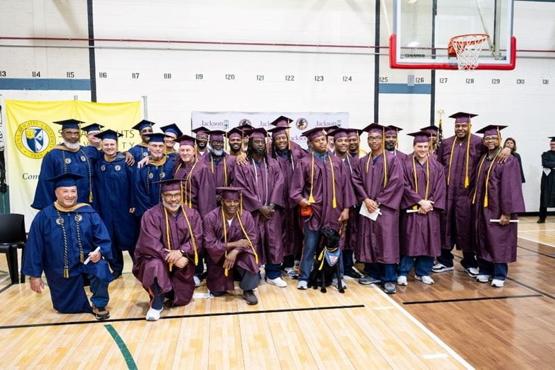 Recent college graduates in their caps and gowns gather for a photo together.