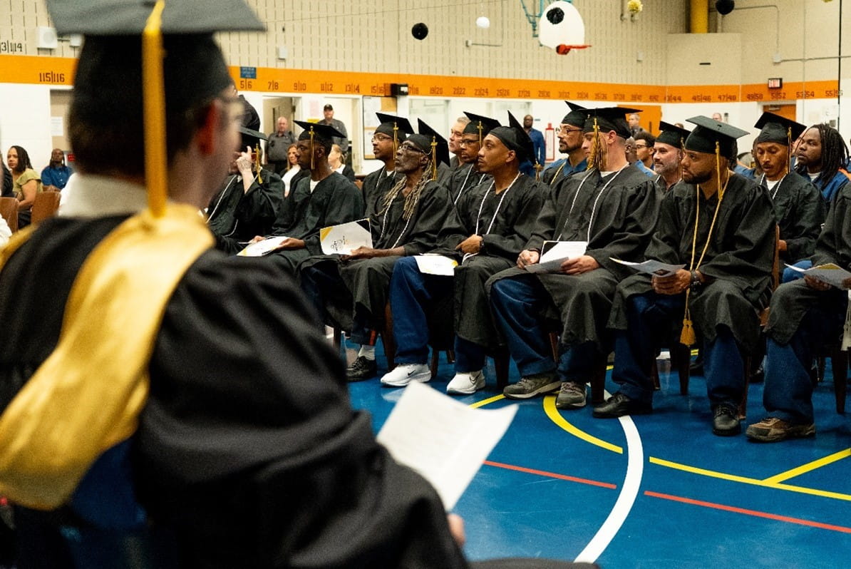 College graduates in their caps and gowns, seated in an auditorium