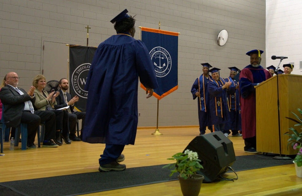 Graduate crossing a stage in his cap and gown